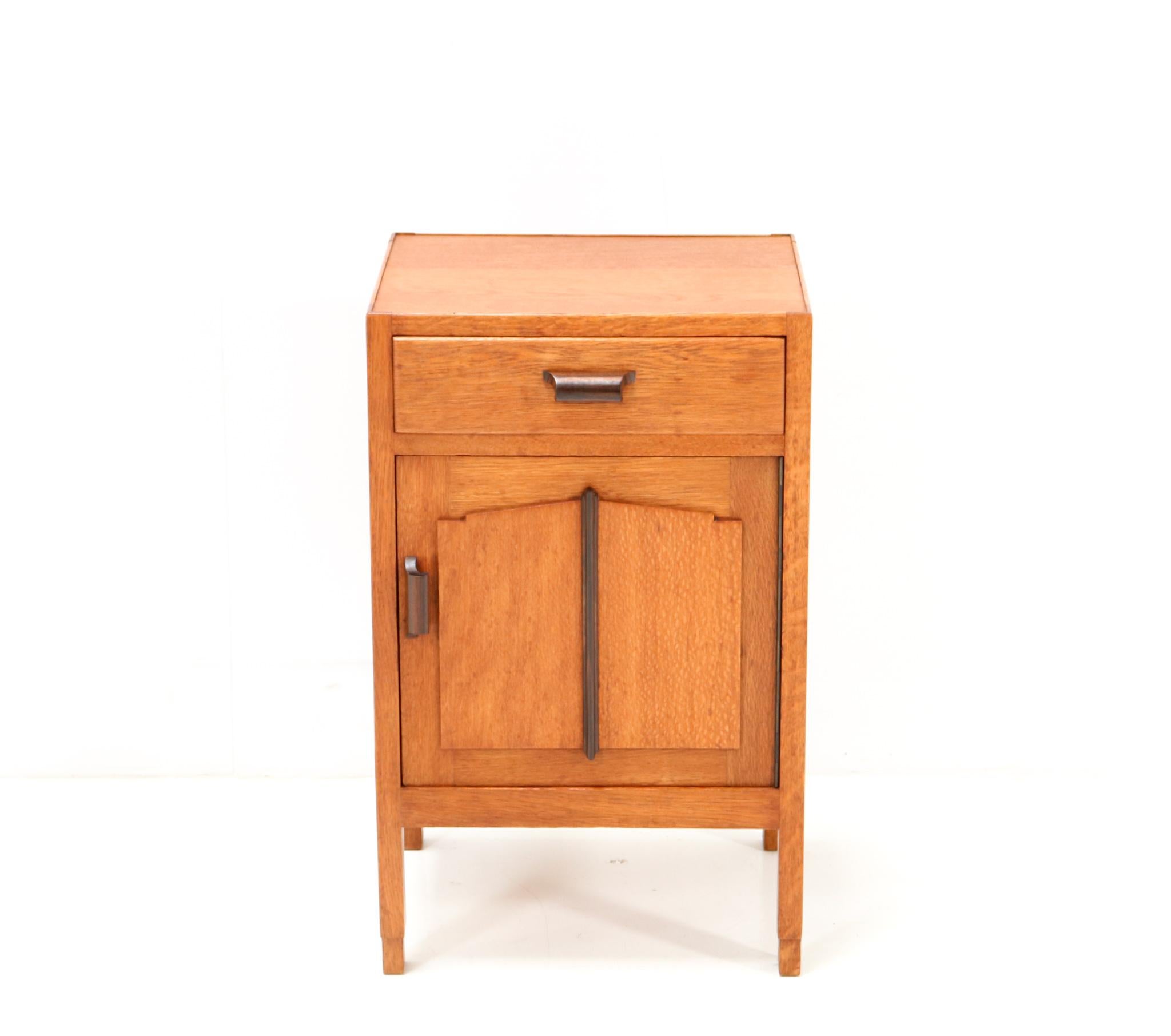 Stunning Art Deco Amsterdamse School nightstand or bedside table.
Striking Dutch design from the 1920s.
Solid oak with original solid macassar ebony handles on drawer and door.
The door has also a solid macassar ebony element in the middle of the