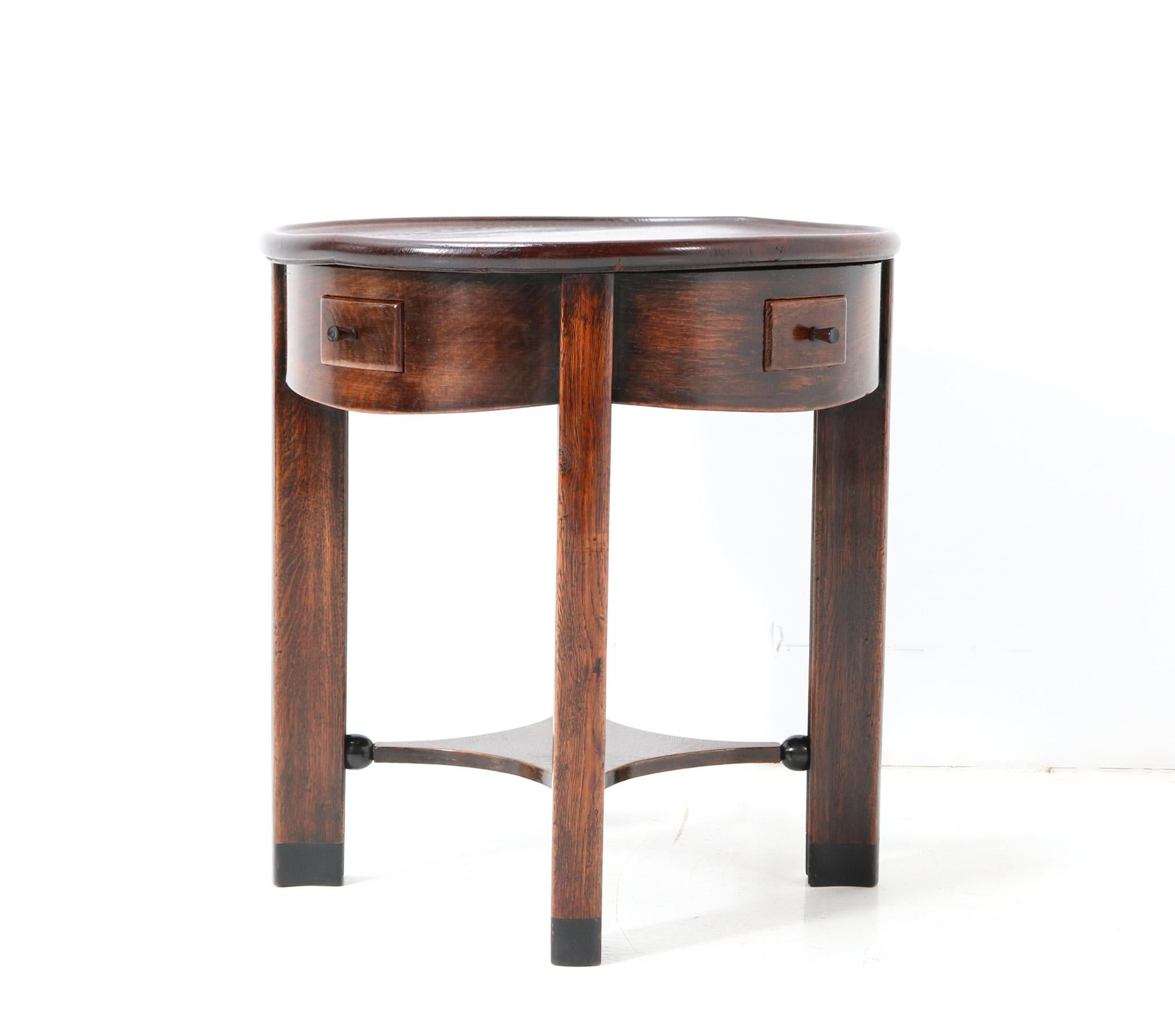 Magnificent and ultra rare Art Deco Amsterdamse School side table.
Design by Piet Kramer for N.V. v/h A.M. Randoe en Zonen Haarlem.
Solid oak frame with four original drawers with four original macassar ebony knobs.
The unusual design with the