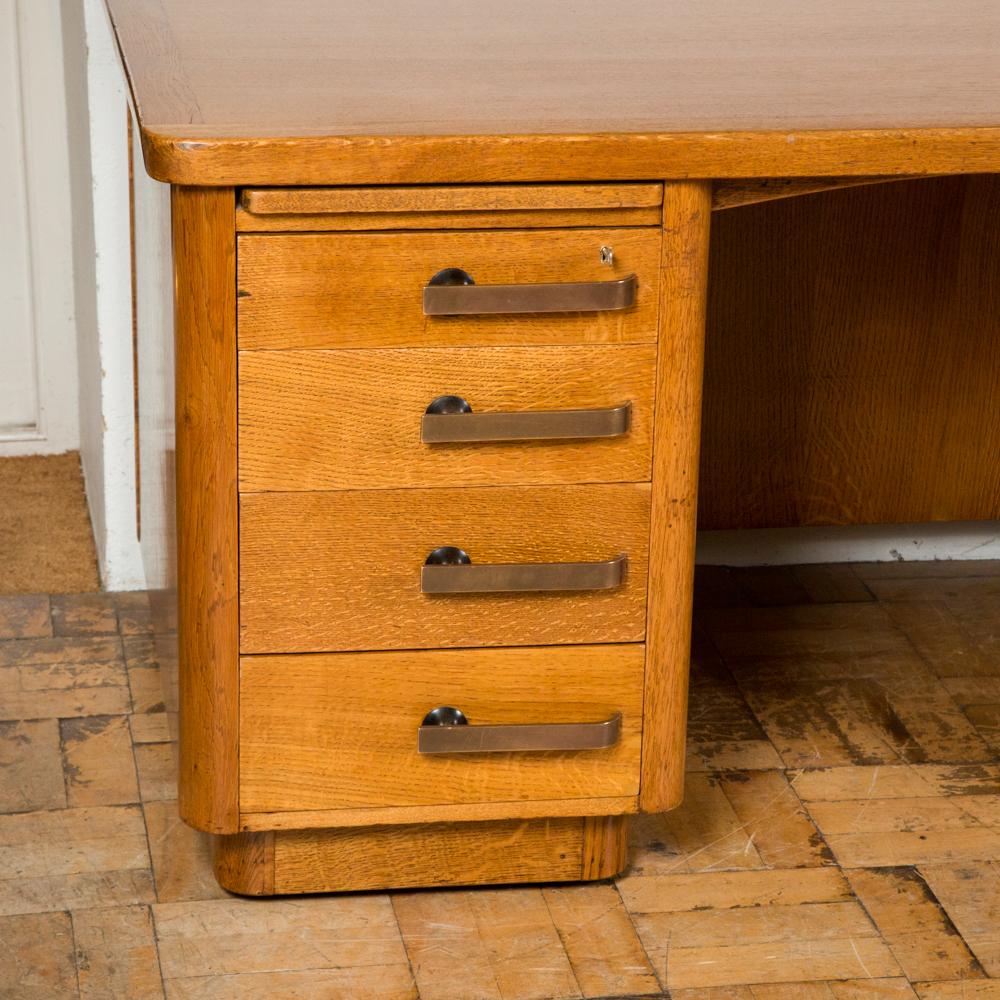 A freestanding oak Art Deco style pedestal desk with bronze handles by Abbess.

Each pedestal having one writing slide over four drawers with bronze handles, the top drawer on each side locks.

Abbess Furniture was established by Charles Nash