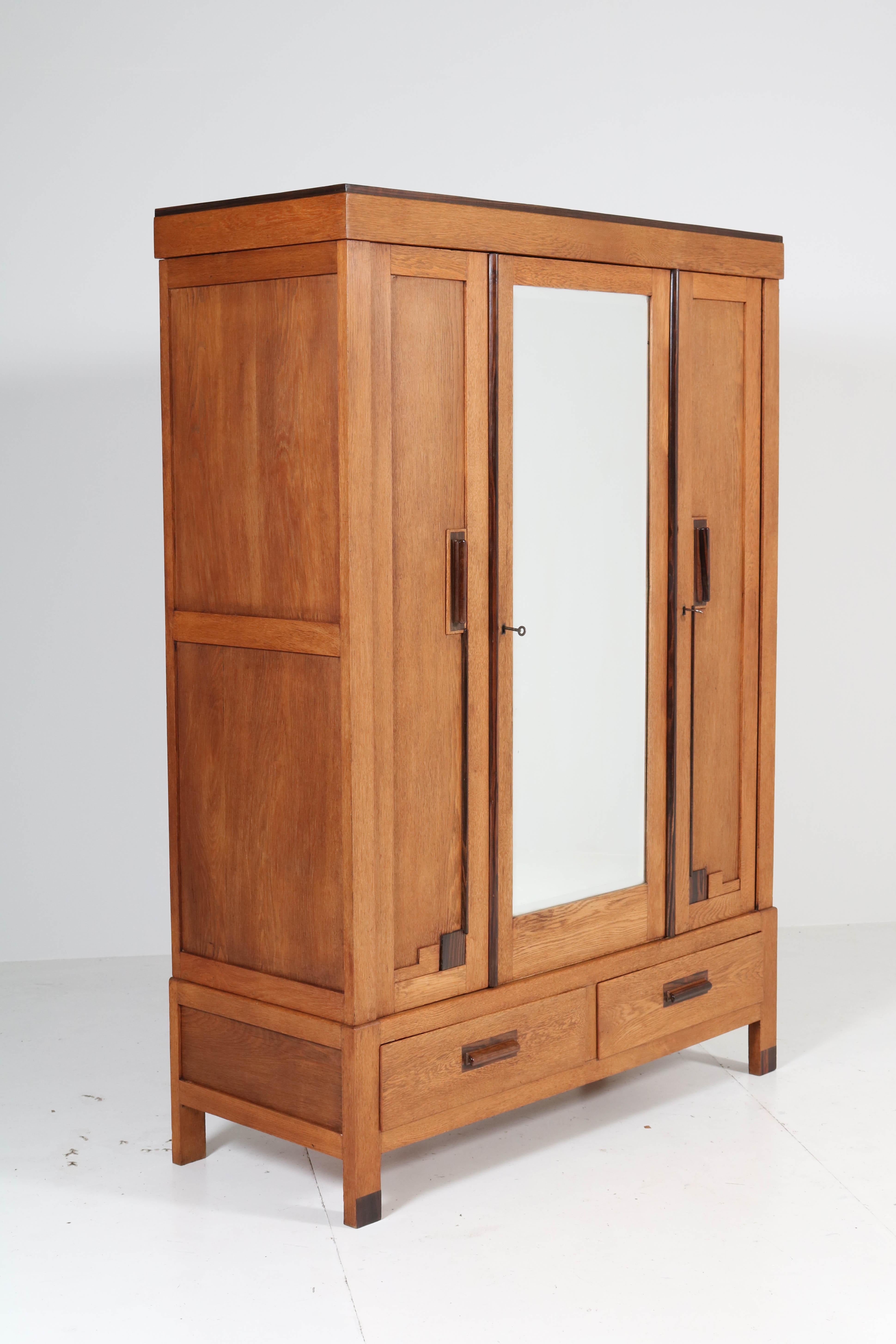 Wonderful Art Deco Haagse School armoire or wardrobe.
Striking Dutch design from the twenties.
Oak with solid Macassar ebony handles.
The brass bar for hanging clothes is behind the left door and the door
with the original beveled