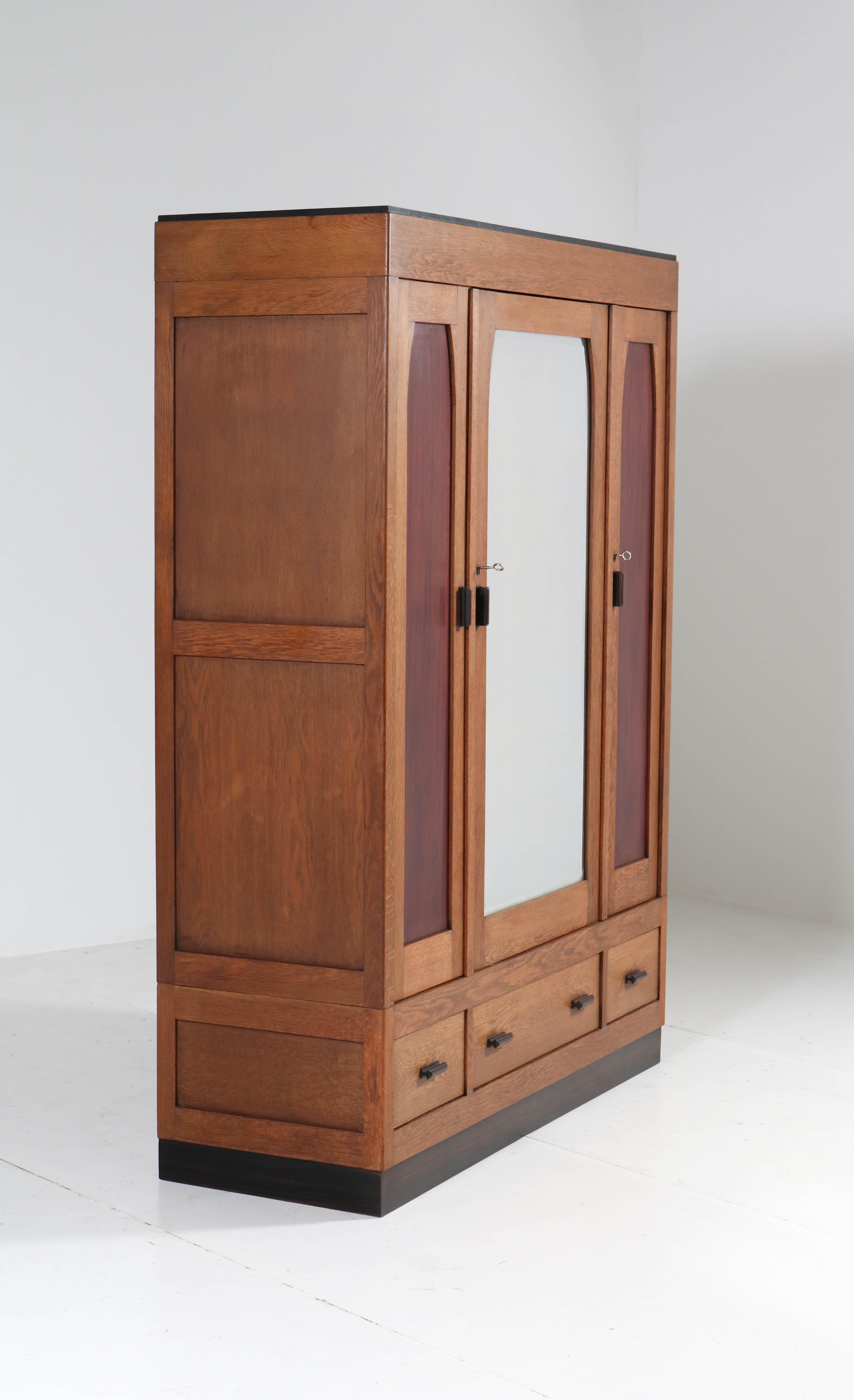 Wonderful and rare Art Deco Haagse School armoire or wardrobe.
Striking Dutch design from the 1920s.
Oak with original solid ebony Macassar handles on doors and drawers.
The two smaller doors have original mahogany panels.
Three original oak