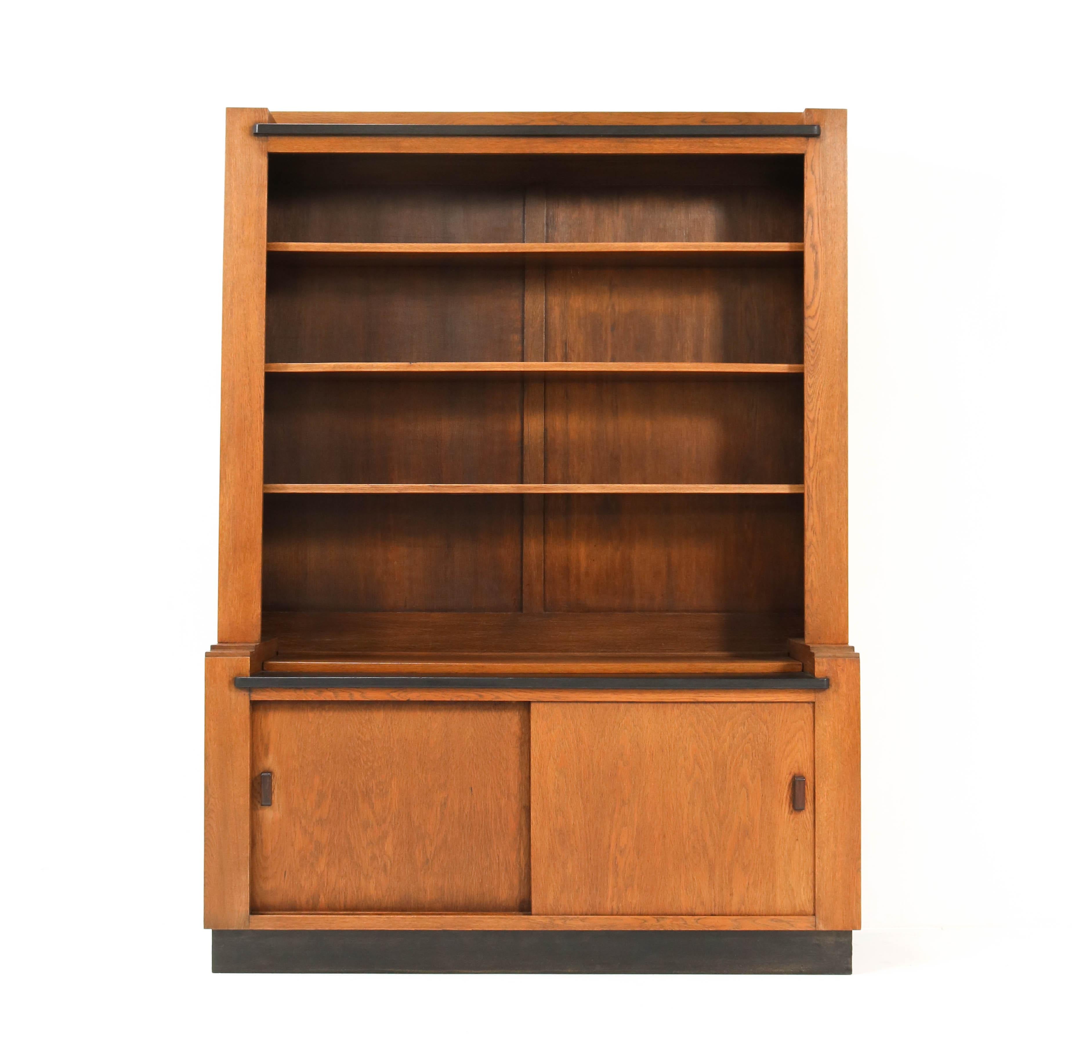 Magnificent and rare Art Deco Haagse School bookcase.
Design by Cor Alons for L.O.V. Oosterbeek.
Striking Dutch design from the 1920s.
Solid oak with original Macassar ebony handles.
Original lacquered black lining.
Three original solid oak