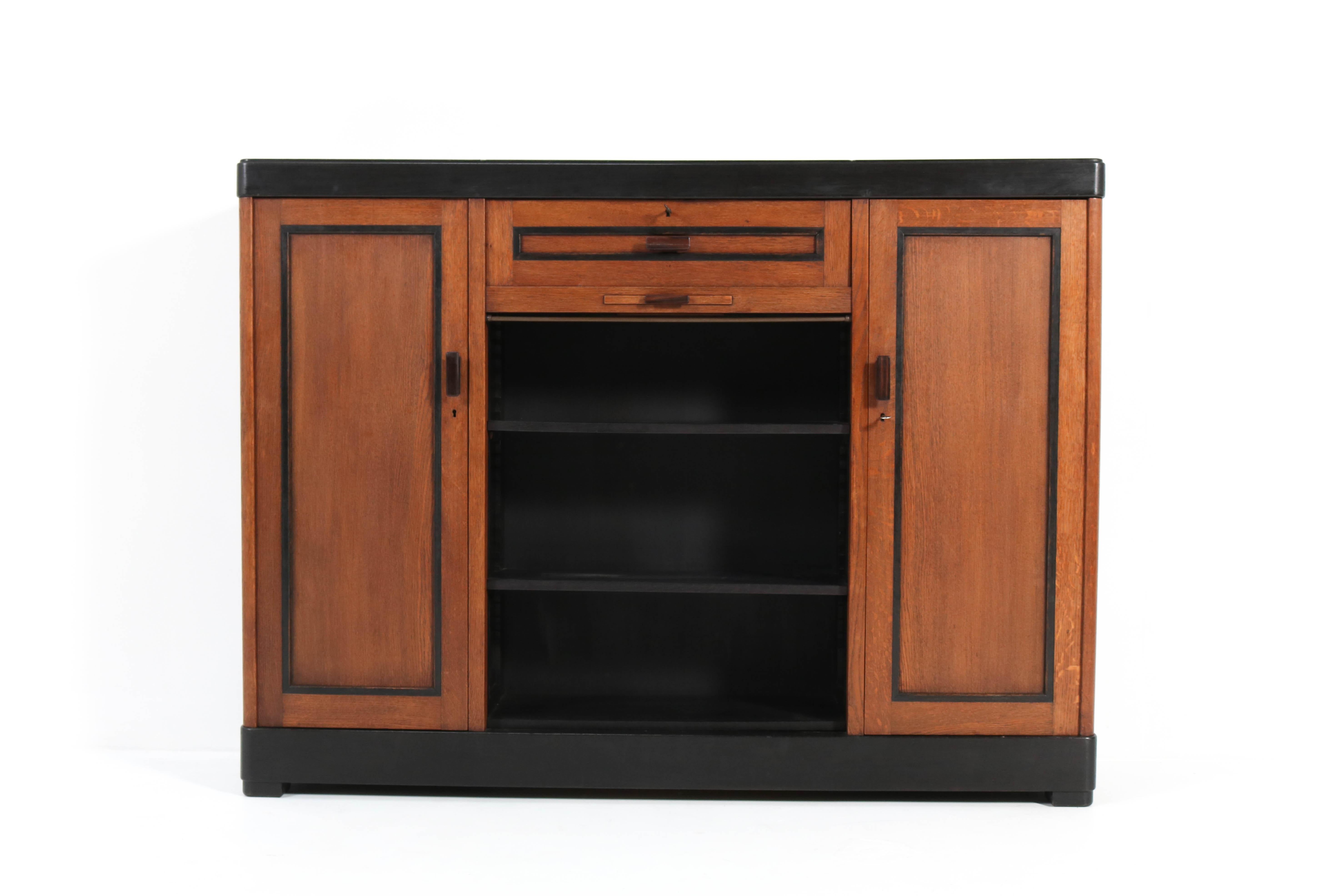 Magnificent and rare Art Deco Haagse School bookcase.
Design by Frits Spanjaard for L.O.V. Oosterbeek.
Striking Dutch design from the twenties.
Solid oak with original Macassar ebony handles and original black lacquered 
lining.
Marked with