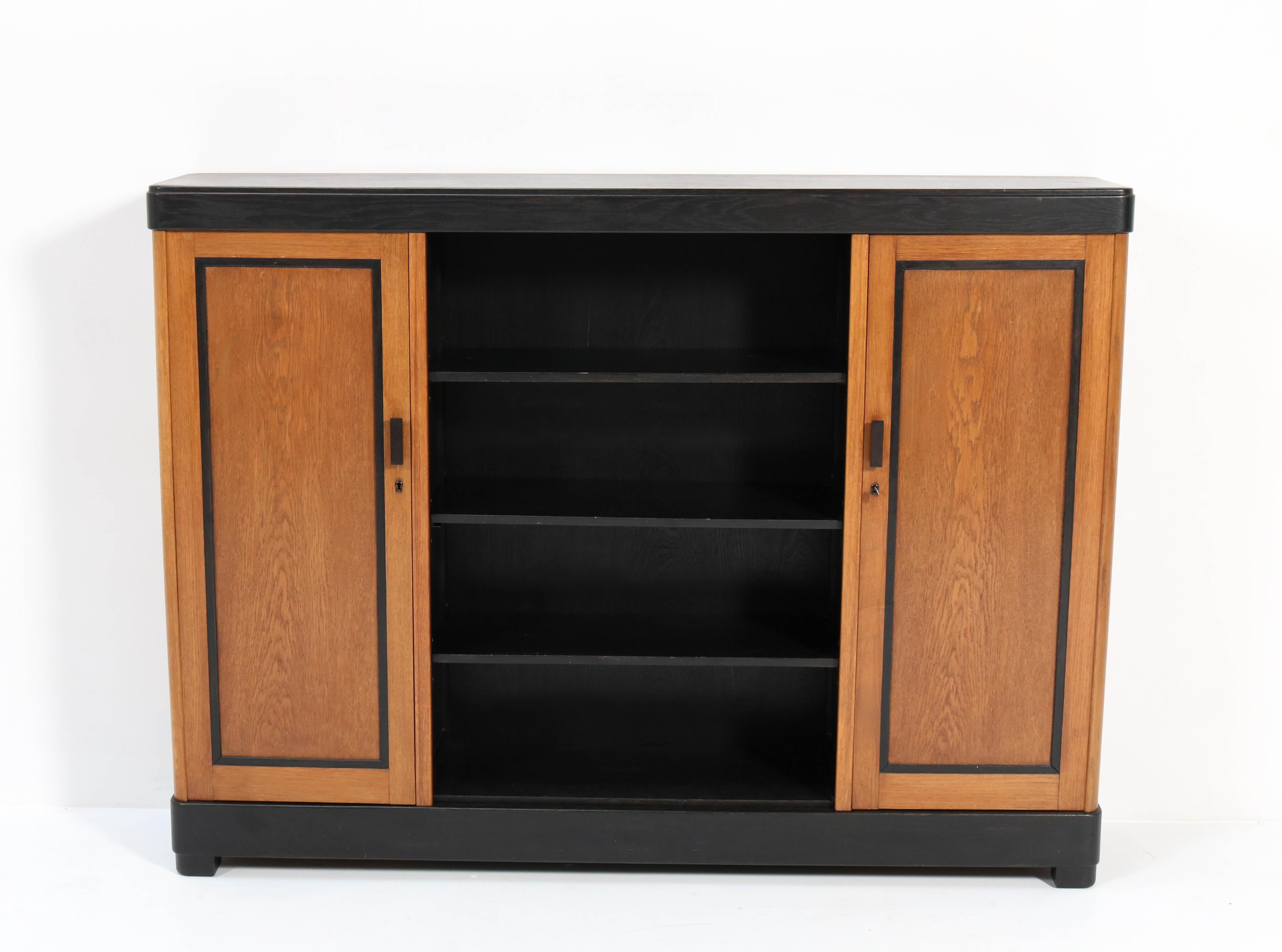 Wonderful and rare Art Deco Haagse School bookcase.
Design by Frits Spanjaard for L.O.V. Oosterbeek.
Striking Dutch design from the twenties.
Solid oak with original black lacquered handles and lining.
This wonderful piece of furniture can be