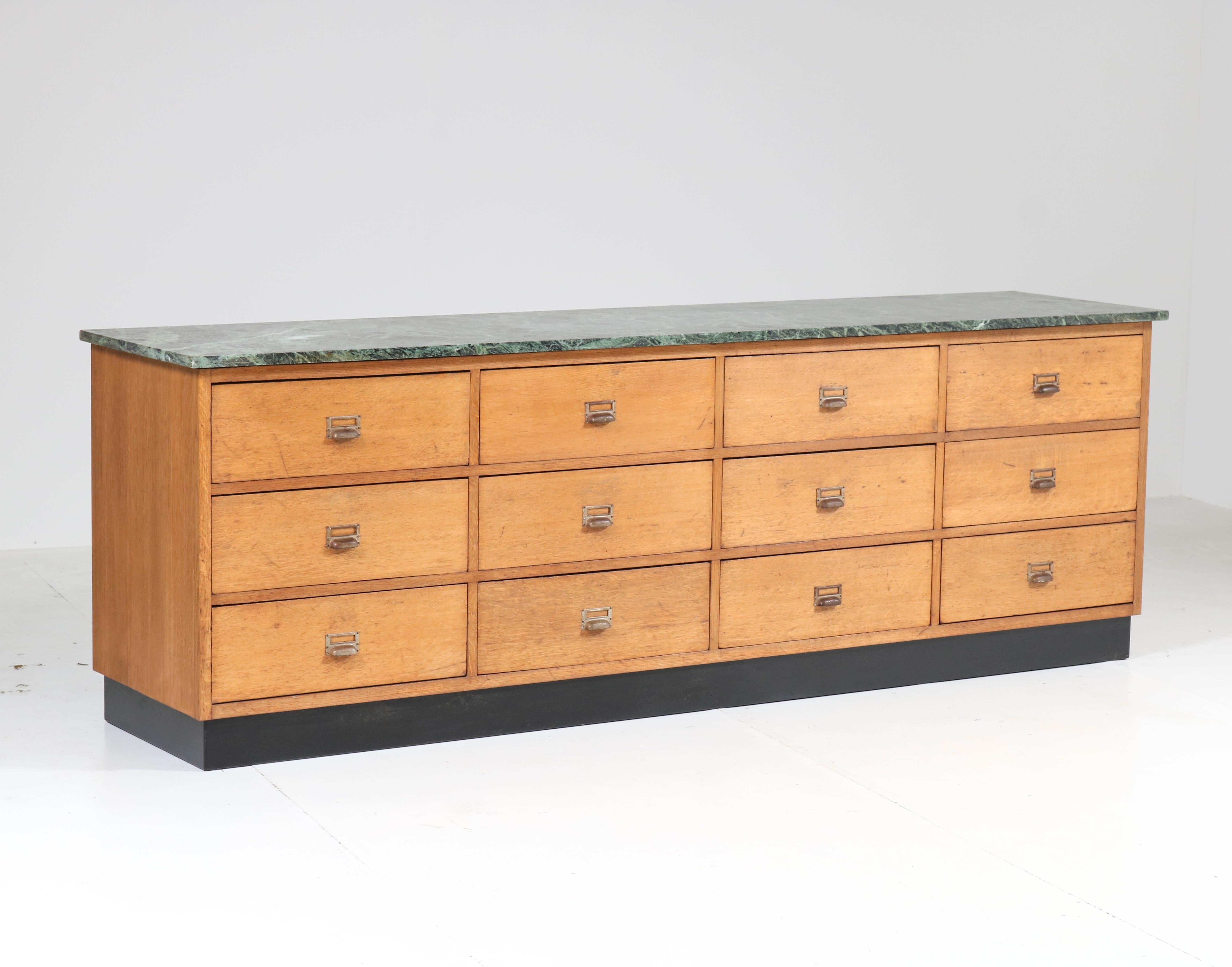Magnificent and rare Art Deco Haagse School counter.
Striking Dutch design from the twenties.
Oak frame with 12 original drawers and Patricia Green marble top.
This wonderful piece of furniture is ideal for a shop, restaurant or kitchen etc.
You