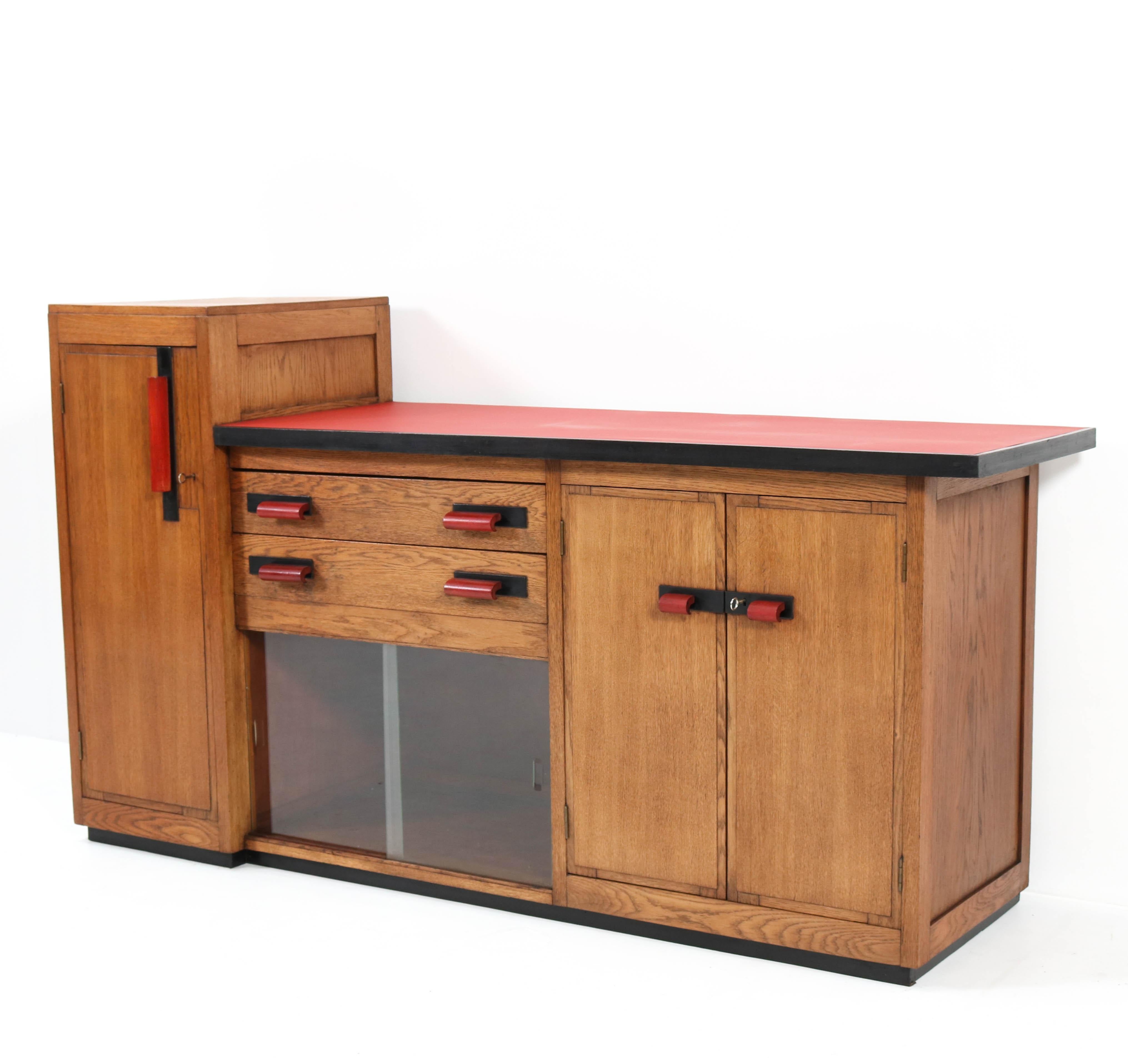 Magnificent and rare Art Deco Haagse School credenza or sideboard.
Design by Jan Brunott.
Striking Dutch design from the 1920s.
Oak with original mahogany handles on doors and drawers.
The top is renewed with red linoleum.
Original glass