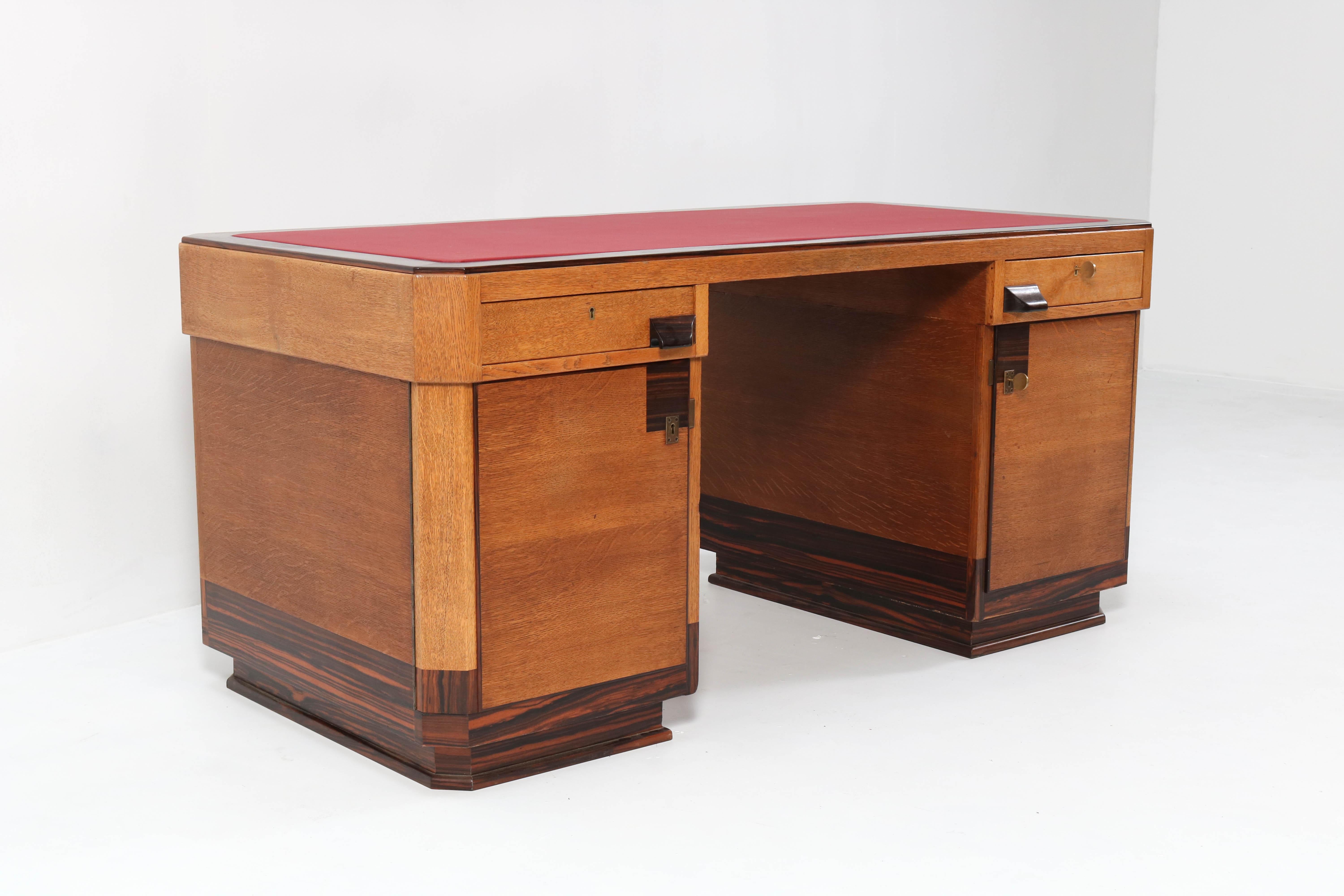 Stunning and rare Art Deco Haagse School pedestal desk.
Design by Anton Lucas Leiden.
Striking Dutch design from the 1920s.
Solid oak with oak veneer and solid ebony Macassar handles and lining.
The top is redone with red faux leather.
This