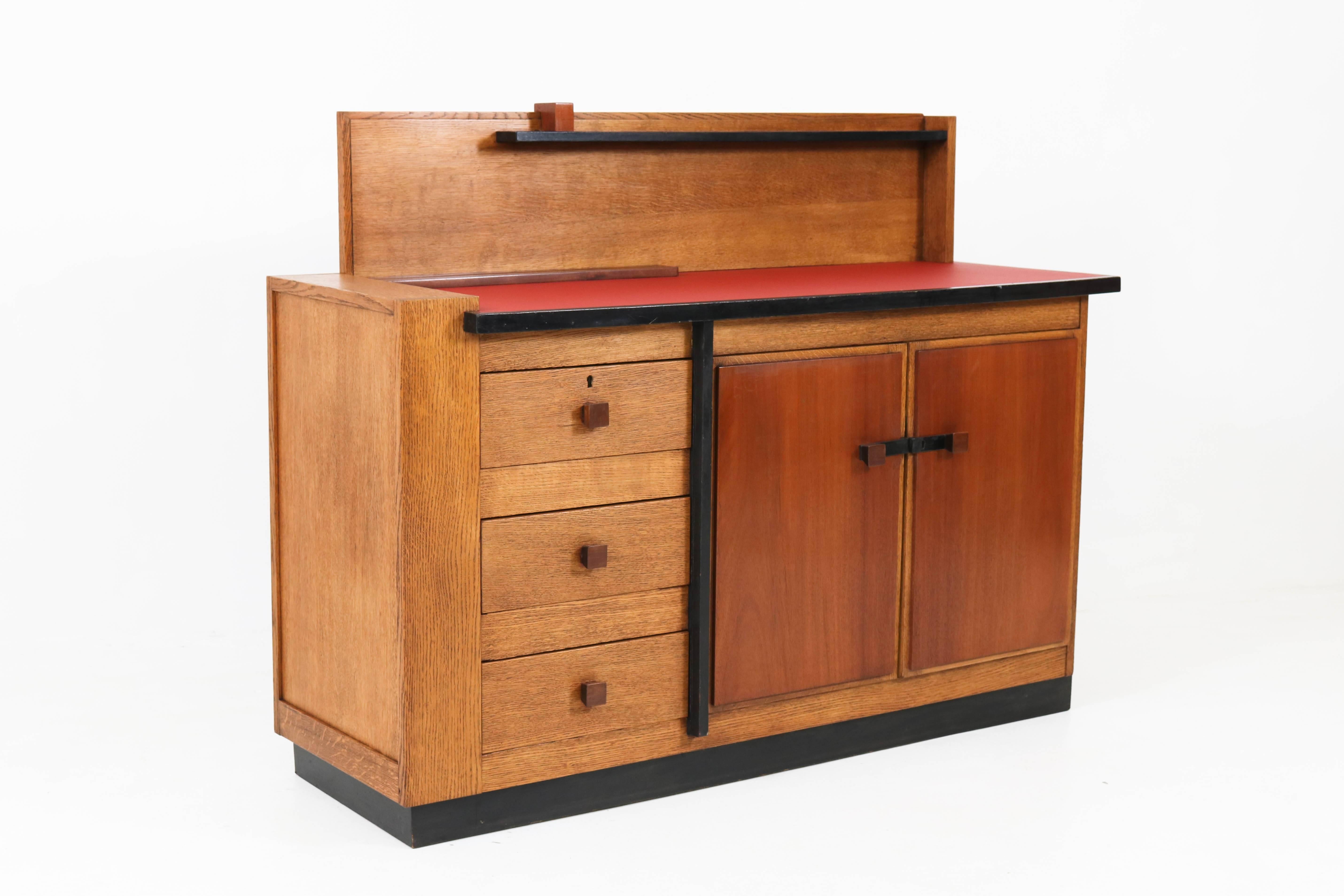 Magnificent and very rare Art Deco Haagse School sideboard or credenza by Jan Brunott, 1920s.
Solid oak with mahogany doors and handles on the three drawers.
The top has new red linoleum.
Original ebonized handles on the doors.
Striking design