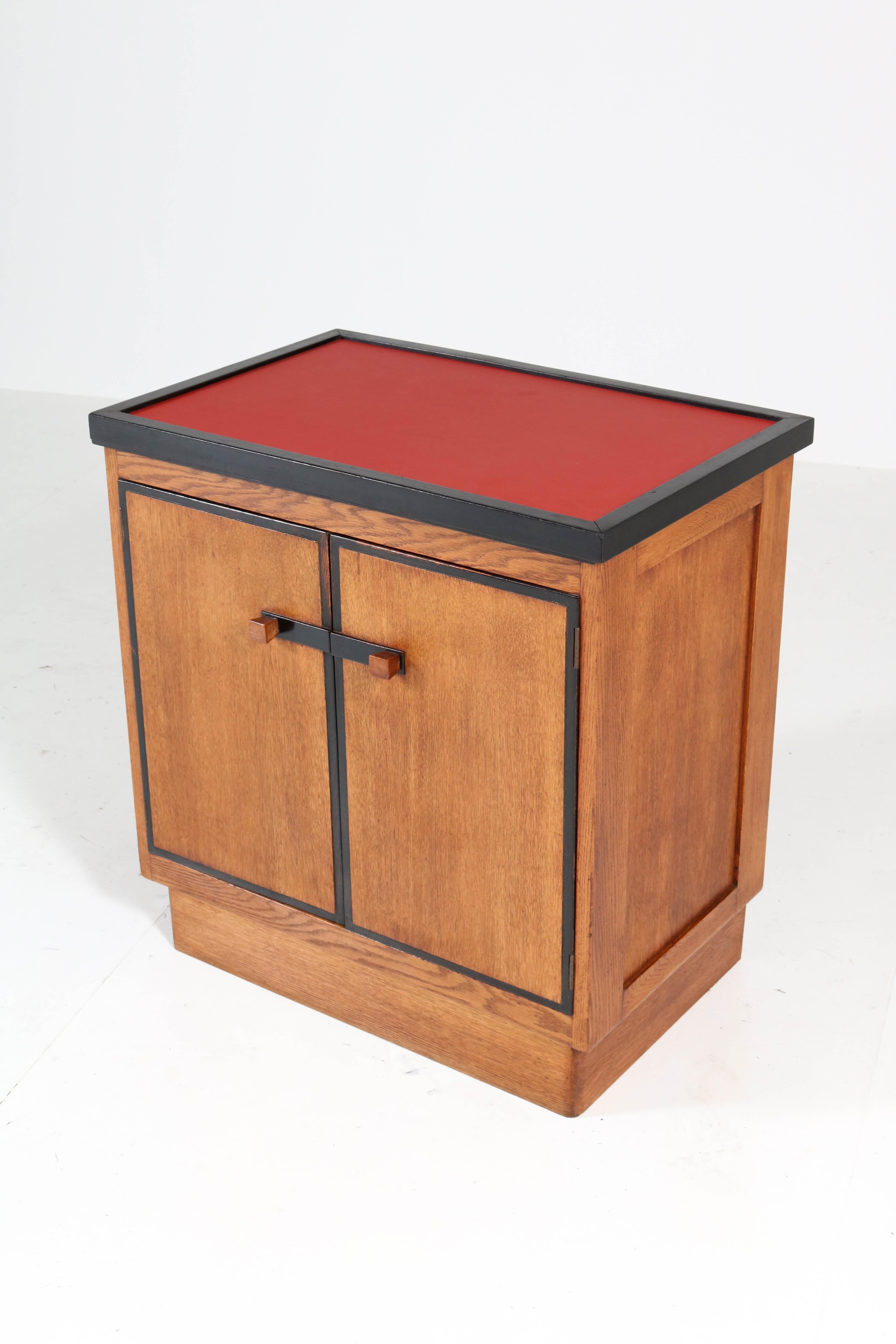 Magnificent and rare Art Deco Haagse School tea cabinet.
Design by Jan Brunott.
Striking Dutch design from the twenties.
Solid oak and oak veneer with original ebonized lining.
The top of the tray is renewed with red linoleum.
Marked with