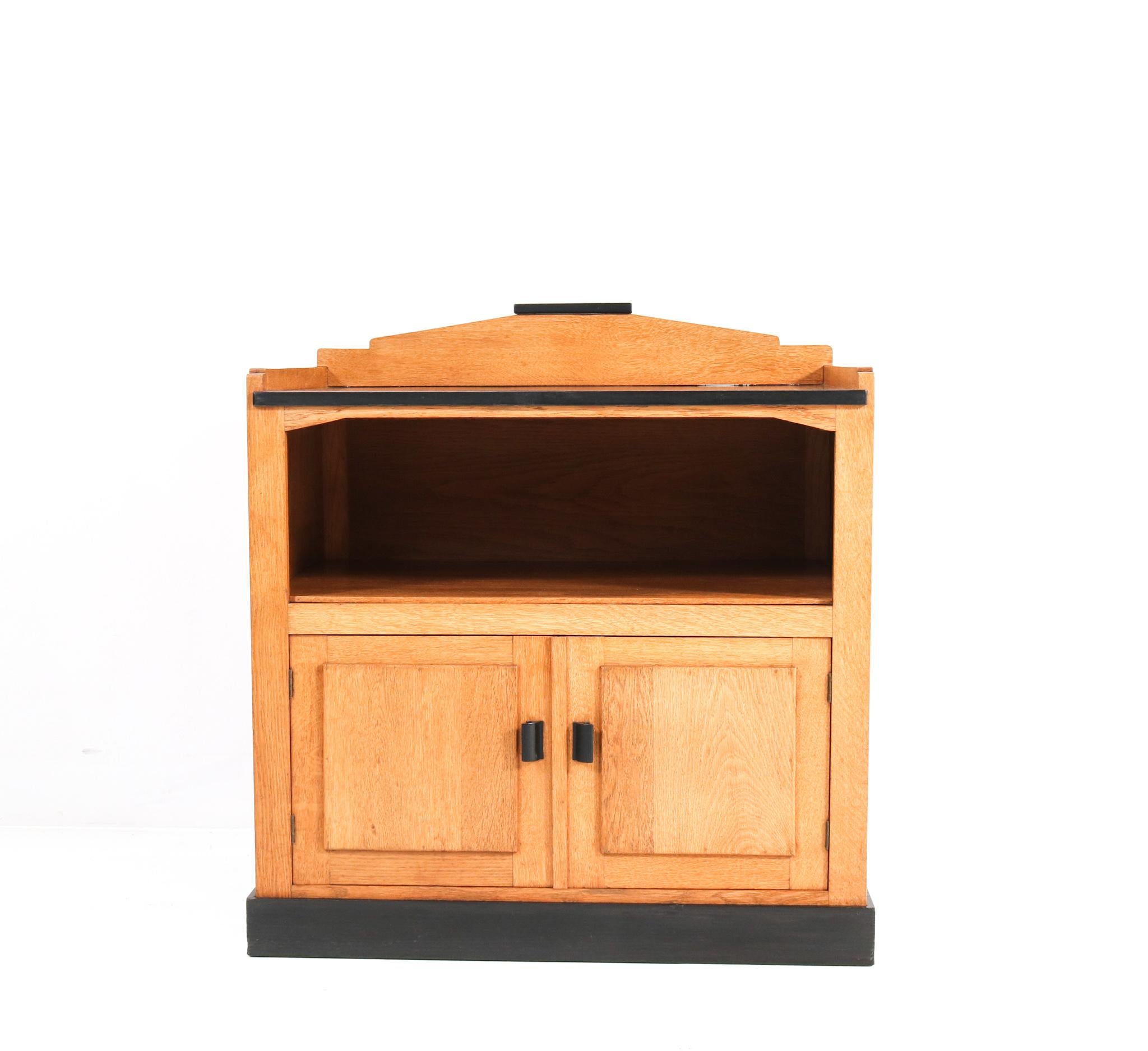 Magnificent and rare Art Deco Haagse School tea cabinet.
Design by Jan Brunott.
Striking Dutch design from the 1920s.
Solid oak with original black linoleum top.
Original black lacquered handles on the doors.
Rare because of the fact that its