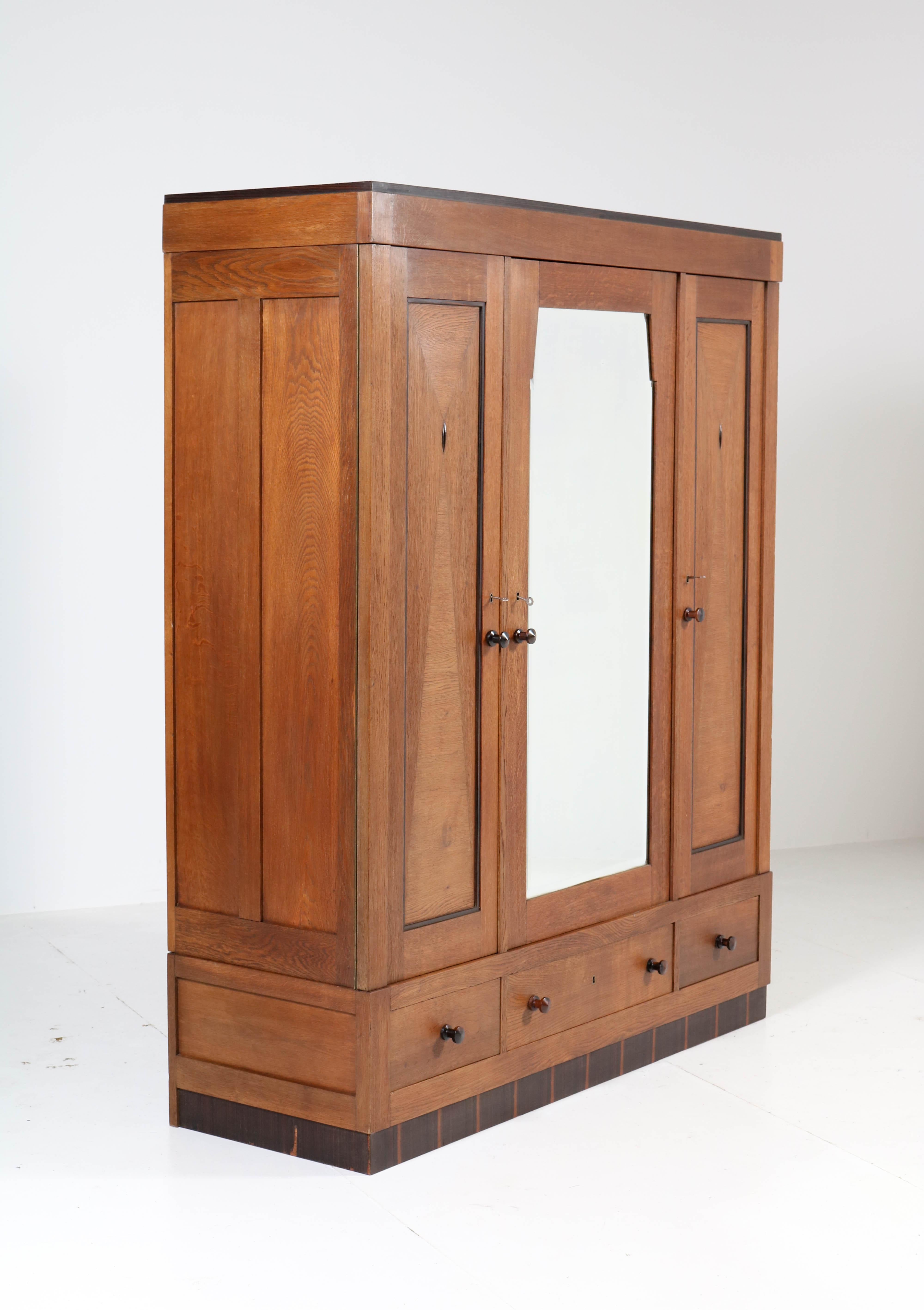 Wonderful Art Deco Haagse School wardrobe or armoir.
Striking Dutch design from the twenties.
Oak with ebony Macassar knobs and lining.
Behind the door with the original beveled mirror you will find three original
wooden shelves.
The other