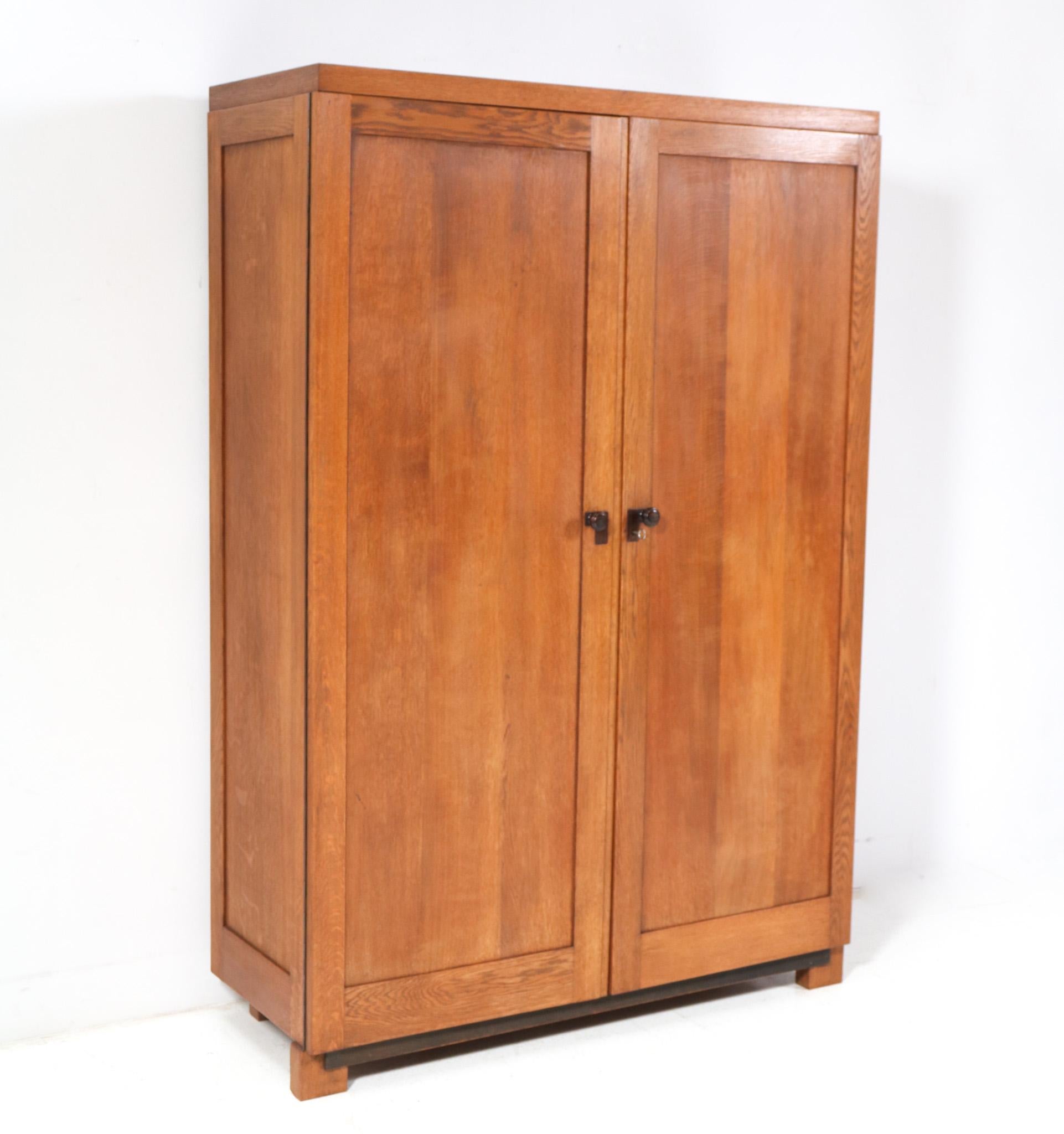 Magnificent and rare Art Deco Modernist armoire or wardrobe.
Striking Dutch design from the 1920s.
Solid oak base with original solid macassar ebony knobs on both doors.
Seven original solid oak shelves.
The top has also two original brass rods for