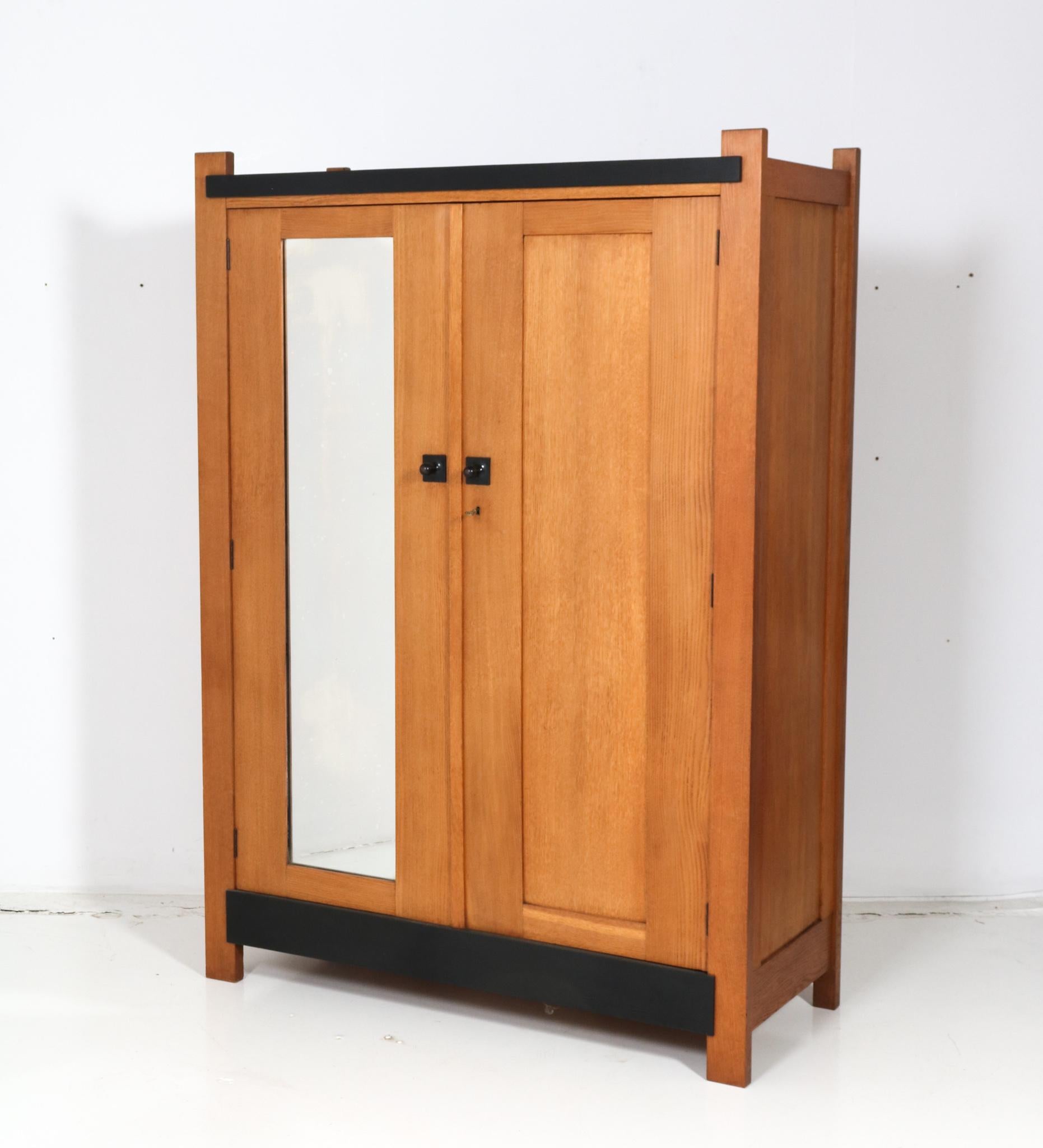 Magnifique et rare armoire moderniste Art Déco.
Design de Hendrik Wouda pour H. Pander & Zonen Den Haag.
Un design néerlandais saisissant des années 1920.
Chêne massif avec boutons d'origine en bois laqué noir.
Le miroir d'origine est toujours