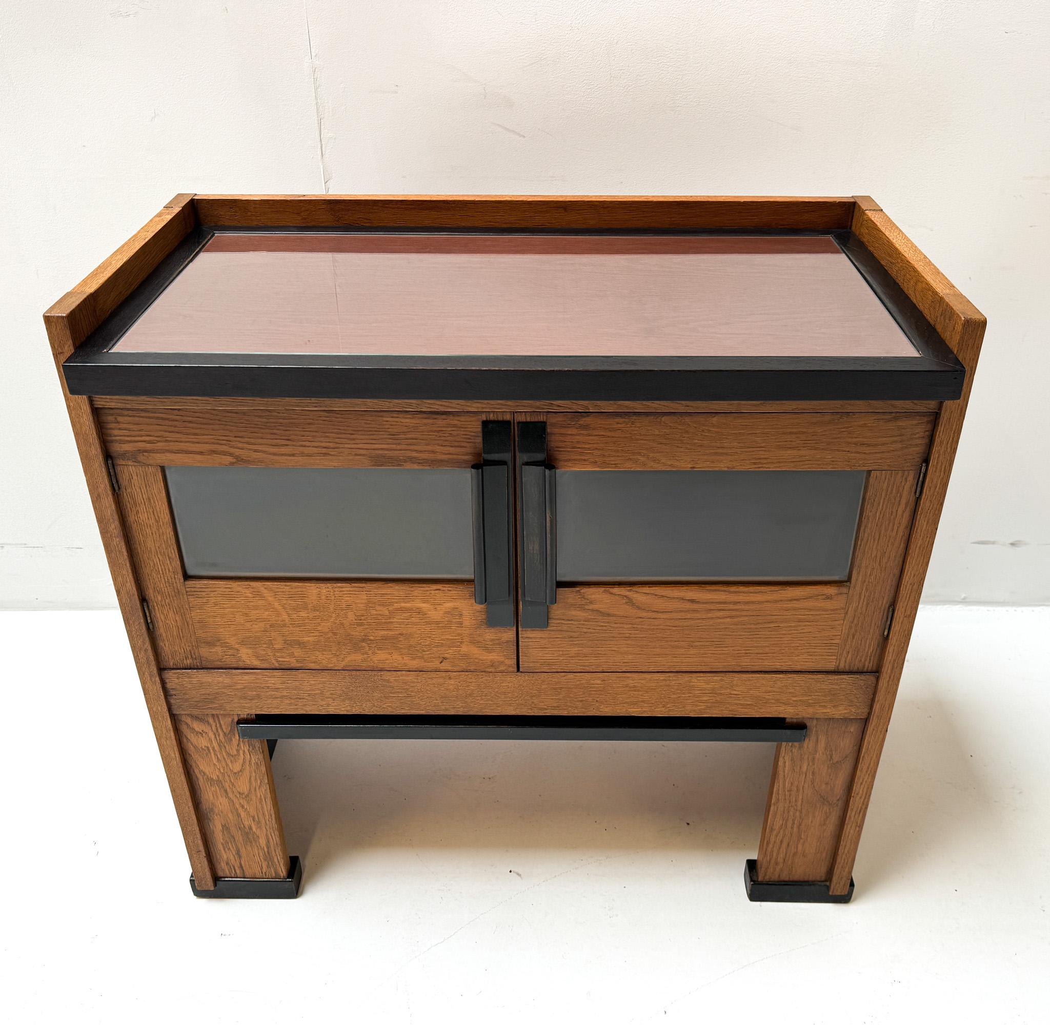Magnificent and ultra rare Art Deco Modernist cabinet.
Design by Jan Brunott.
Striking Dutch design from the 1920s.
Solid oak with original serving tray.
Original black lacquered handles on both doors.
 In very good original condition with minor