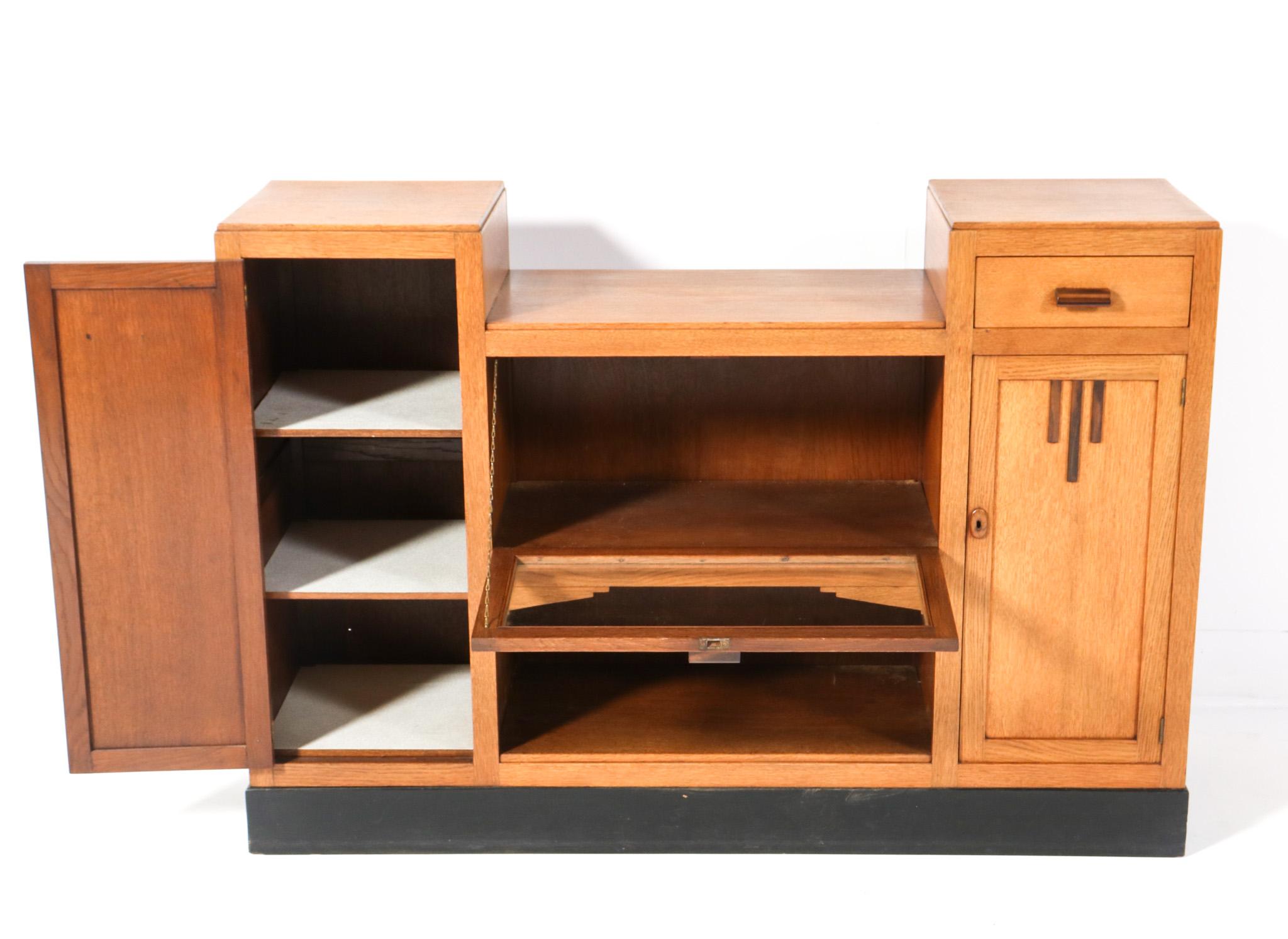 Stunning and rare Art Deco Modernist credenza or sideboard.
Striking Dutch design from the 1920s.
Solid oak base with original solid macassar ebony handles on door with glass and drawer.
Four original wooden shelves behind the left and right
