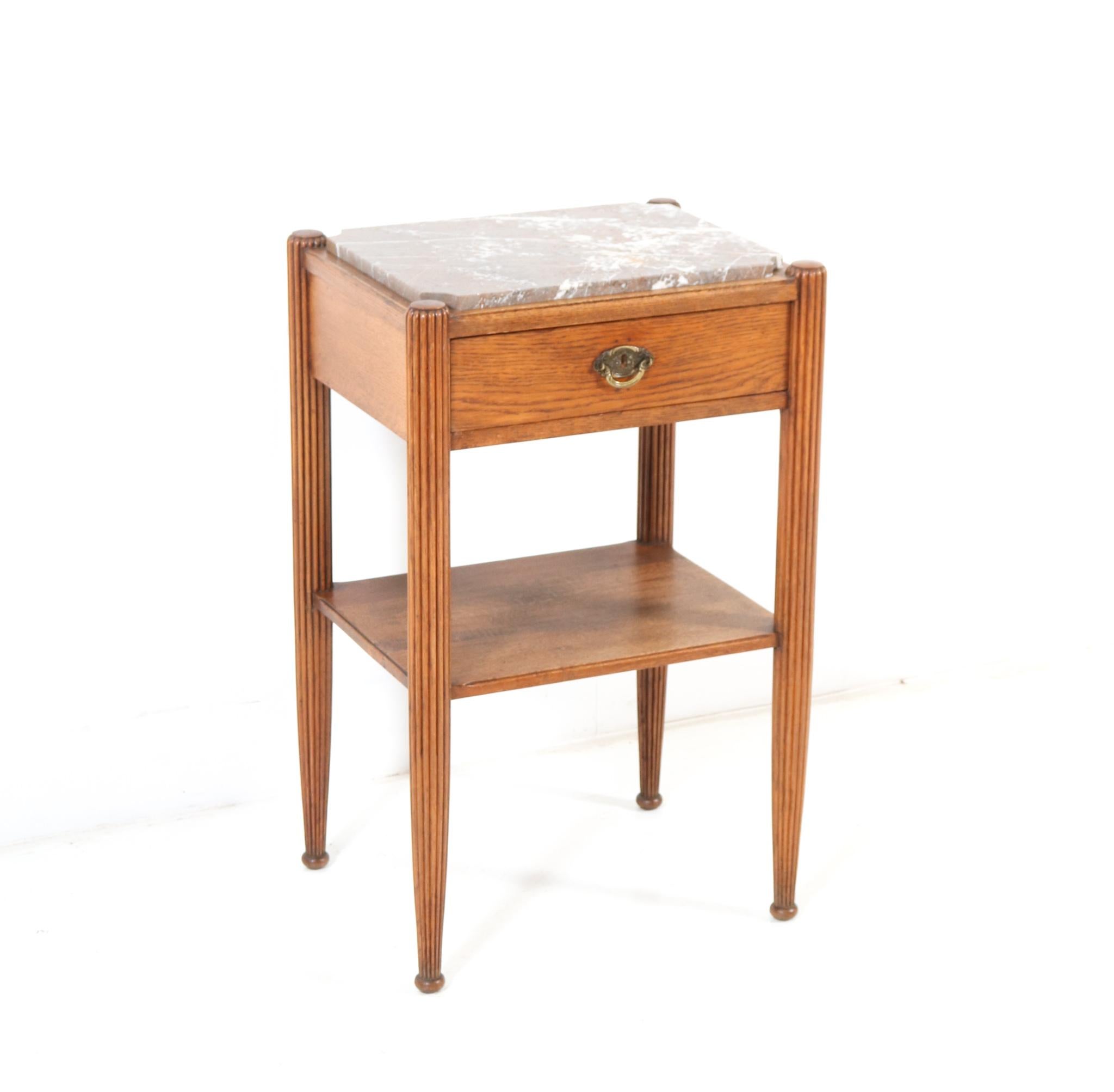 Stunning and rare Art Deco side table.
Striking French design from the 1930s.
Solid oak with original colored marble top.
The drawer has the original brass handle.
This wonderful Art Deco side table is in very good condition with minor wear