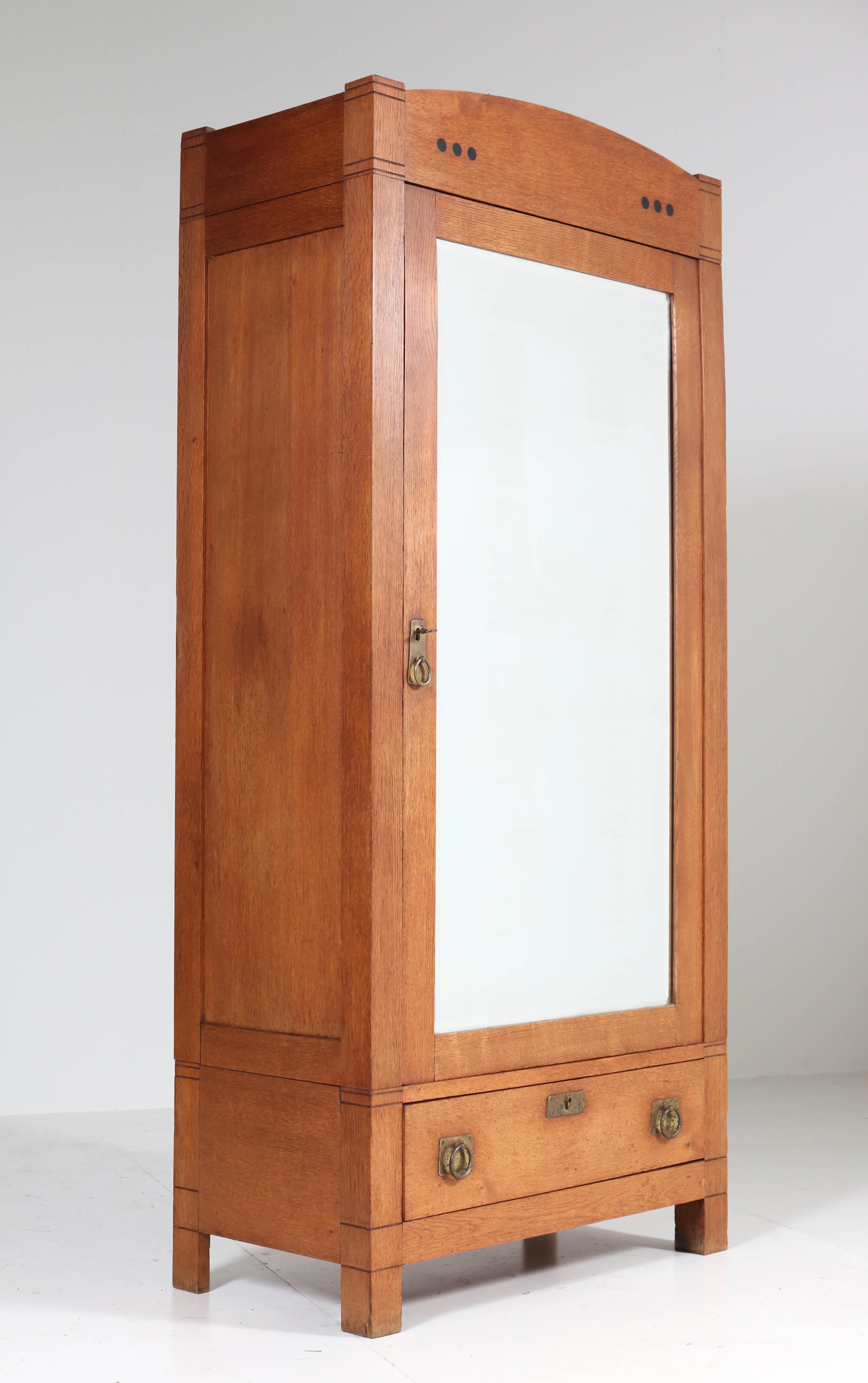 Wonderful Art Nouveau Arts & Crafts armoir or wardrobe.
Striking Dutch design from the 1900s.
Solid oak with original brass handles.
The door has the original beveled glass mirror.
Three wooden shelves, adjustable in height.
This armoir can be