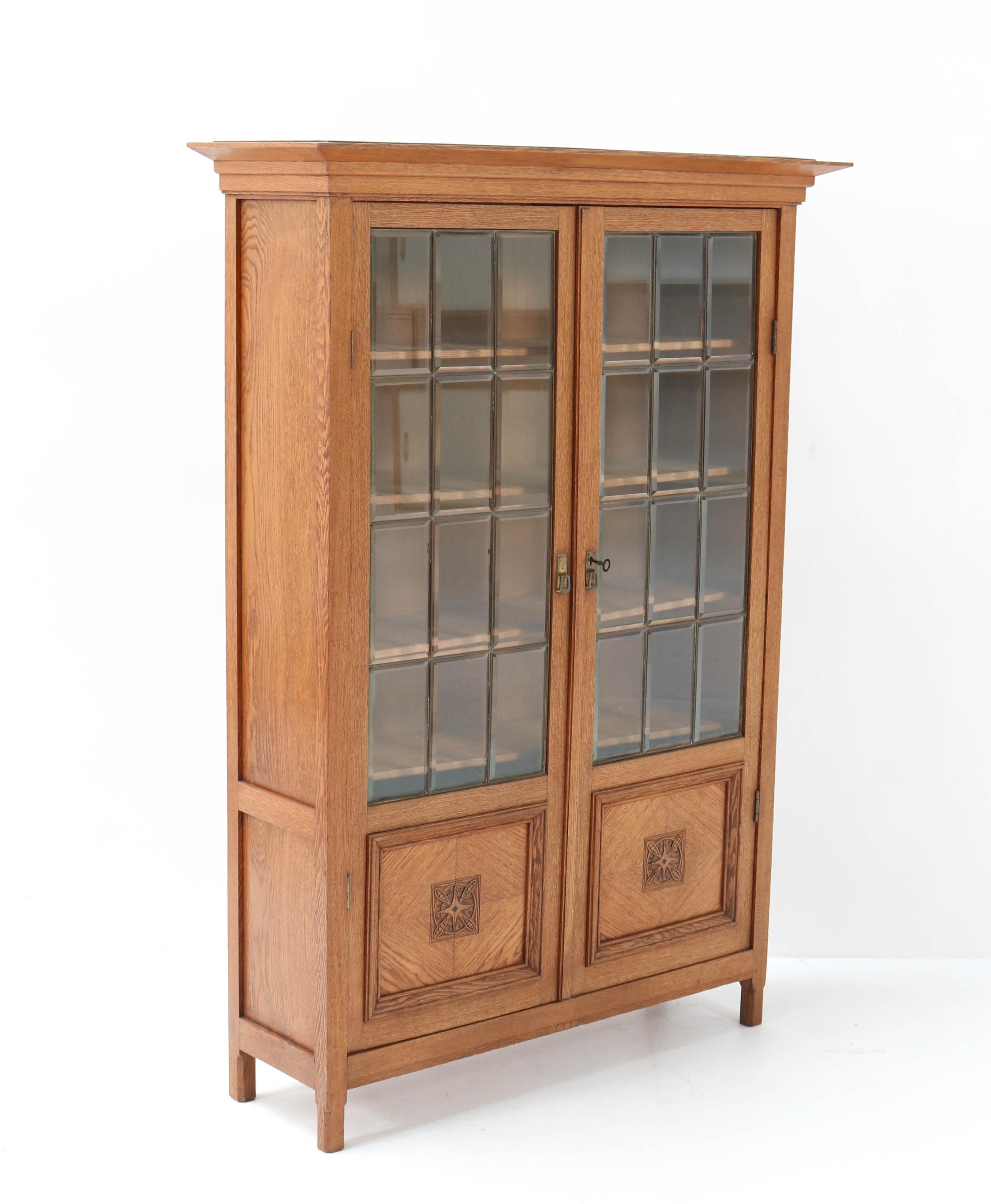 Wonderful and rare Art Nouveau Arts & Crafts bookcase.
Attributed to K.P.C. de Bazel.
Striking Dutch design from the 1900s.
Solid oak with original solid brass handles.
Original beveled glass with brass linings.
Four solid oak shelves