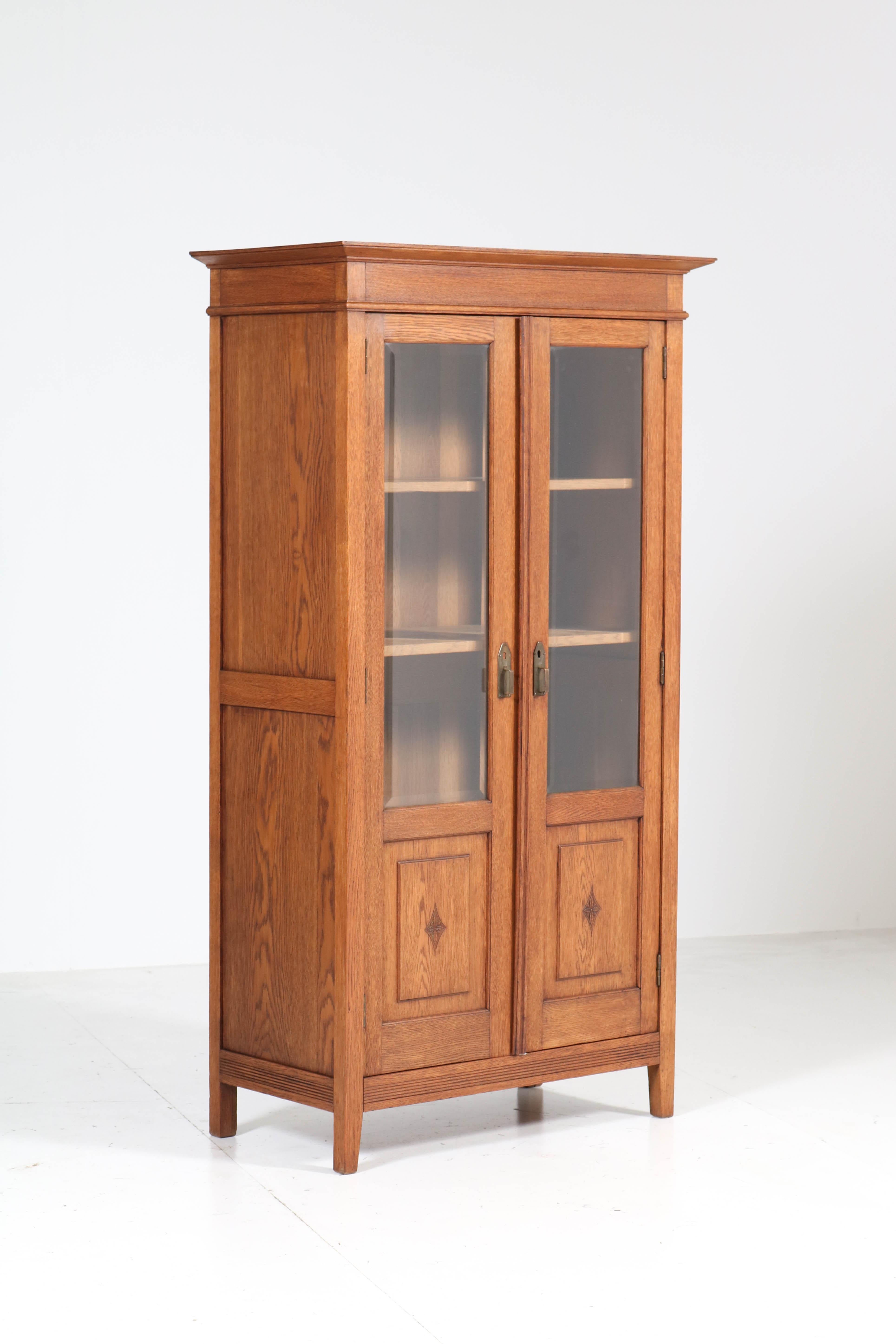 Stunning and rare Art Nouveau Arts & Crafts bookcase.
Striking Dutch design from the 1900s.
Solid oak with original brass handles.
Three original solid oak shelves adjustable in height.
Original beveled glass.
This piece of furniture cannot be