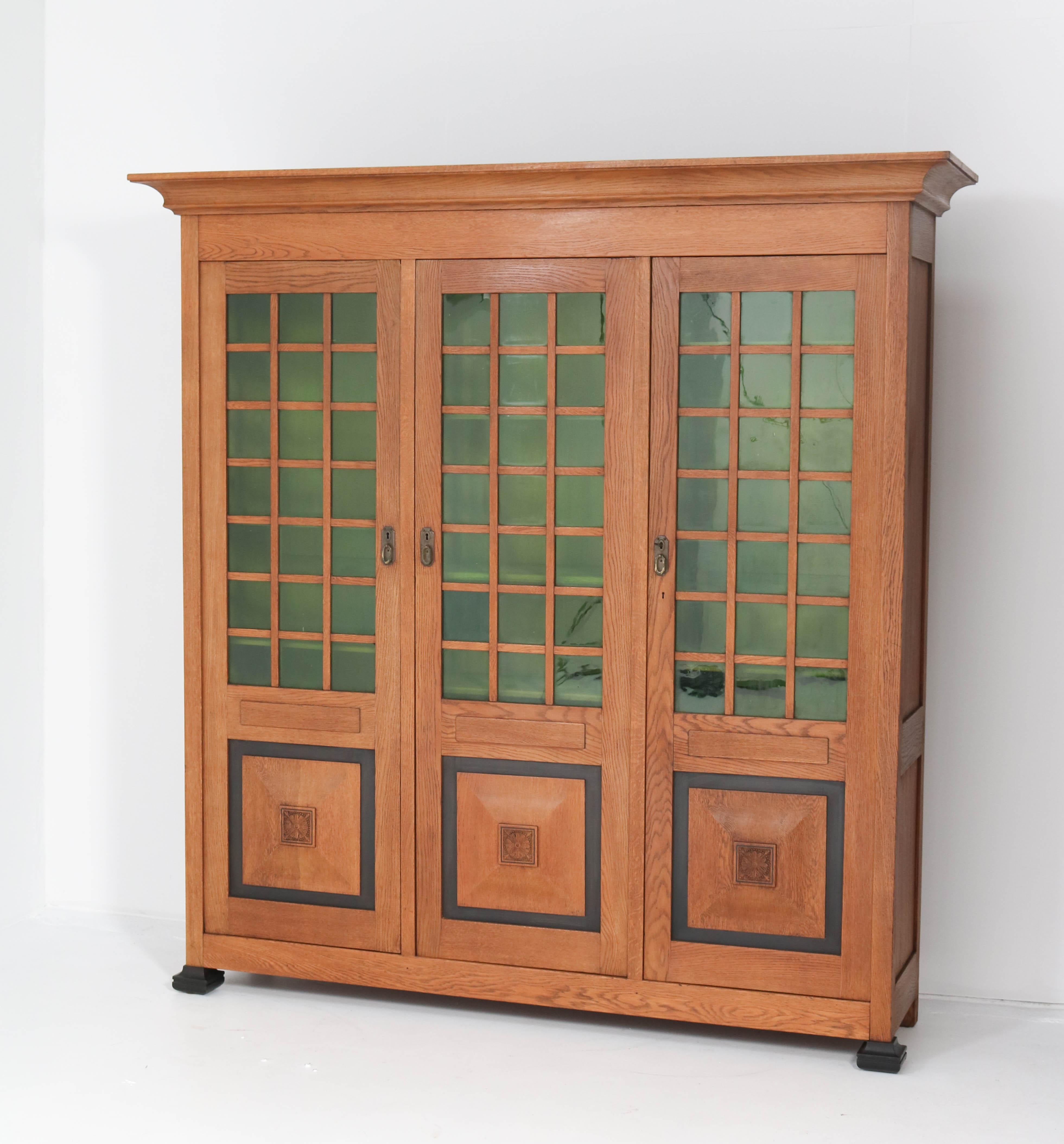 Magnificent and rare Art Nouveau Arts & Crafts library bookcase.
Design by K.P.C. de Bazel.
Striking Dutch design from the 1900s.
Solid oak with original brass handles.
The three doors have original green glass.
This wonderful piece of