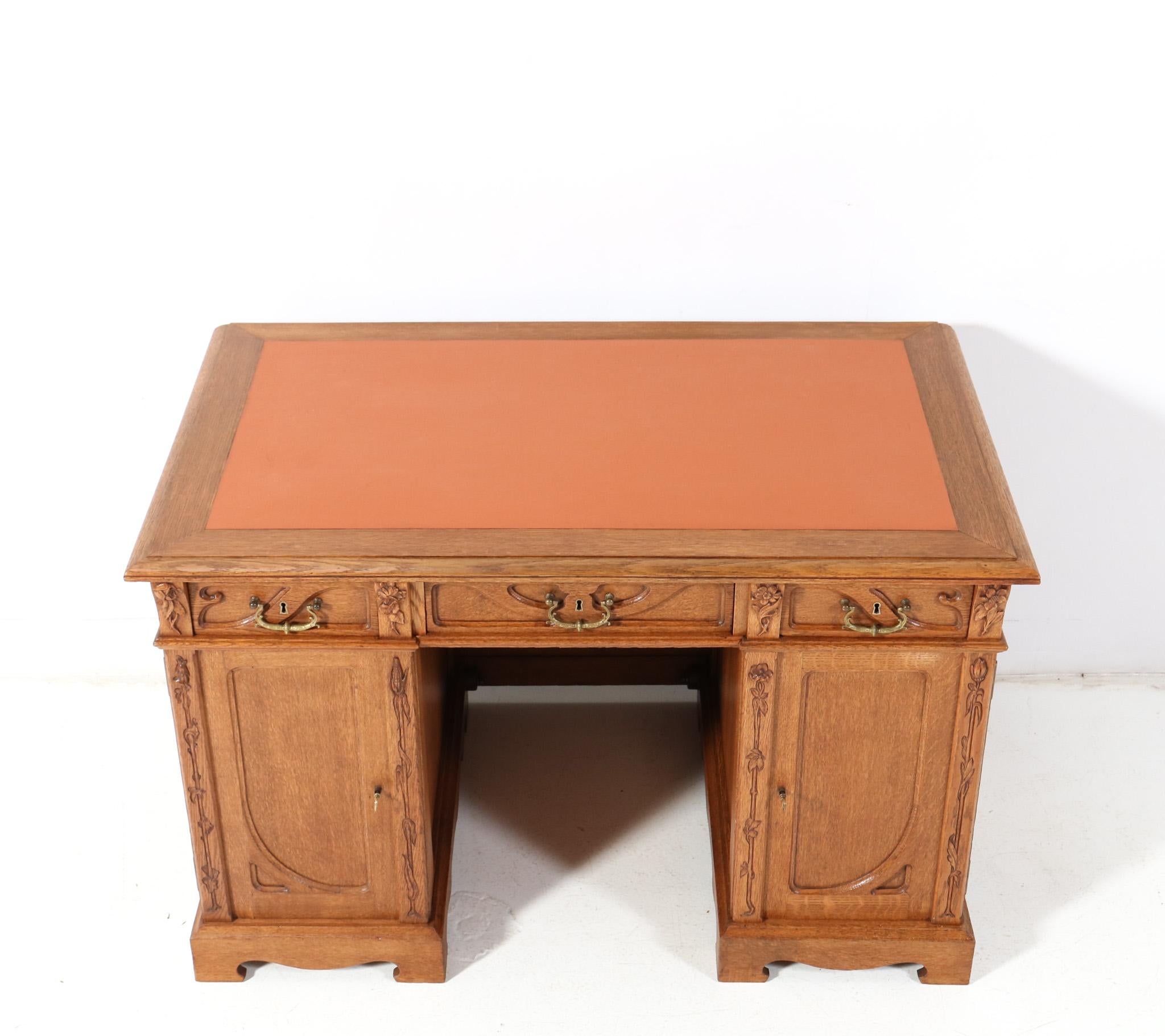 Magnificent and rare Art Nouveau pedestal desk.
Design by J.J. Terburg & Soon Arnhem.
Striking Dutch design from the 1900s.
Solid oak with hand-carved floral decorative elements at the front side.
The three drawers have the original patinated