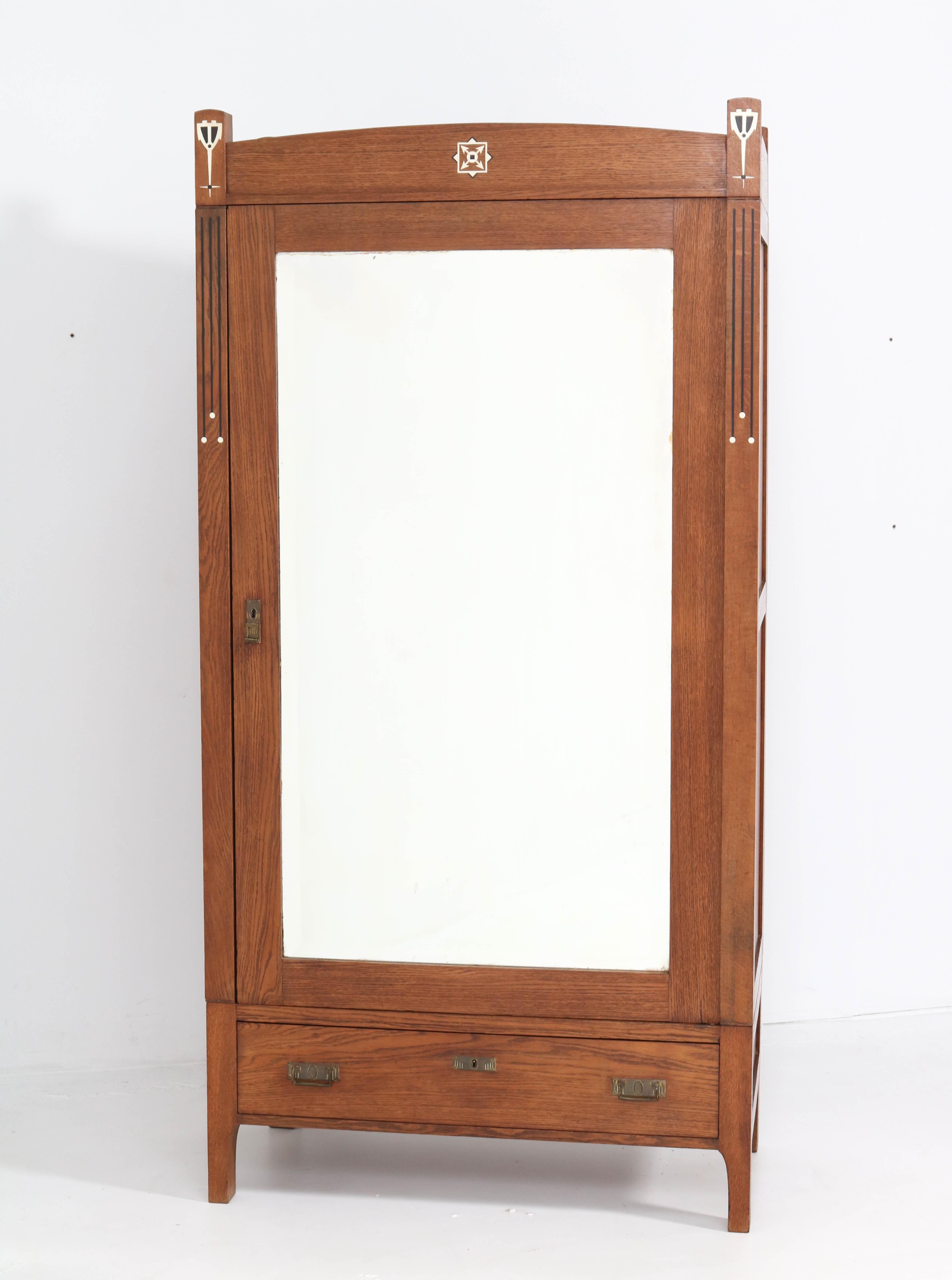 Magnificent and rare Arts & Crafts Art Nouveau armoire or wardrobe.
Striking Dutch design from the 1900s.
In the style of Onder den Sint Maarten.
Solid oak with original brass handles.
Original beveled glass mirror.
Four original wooden