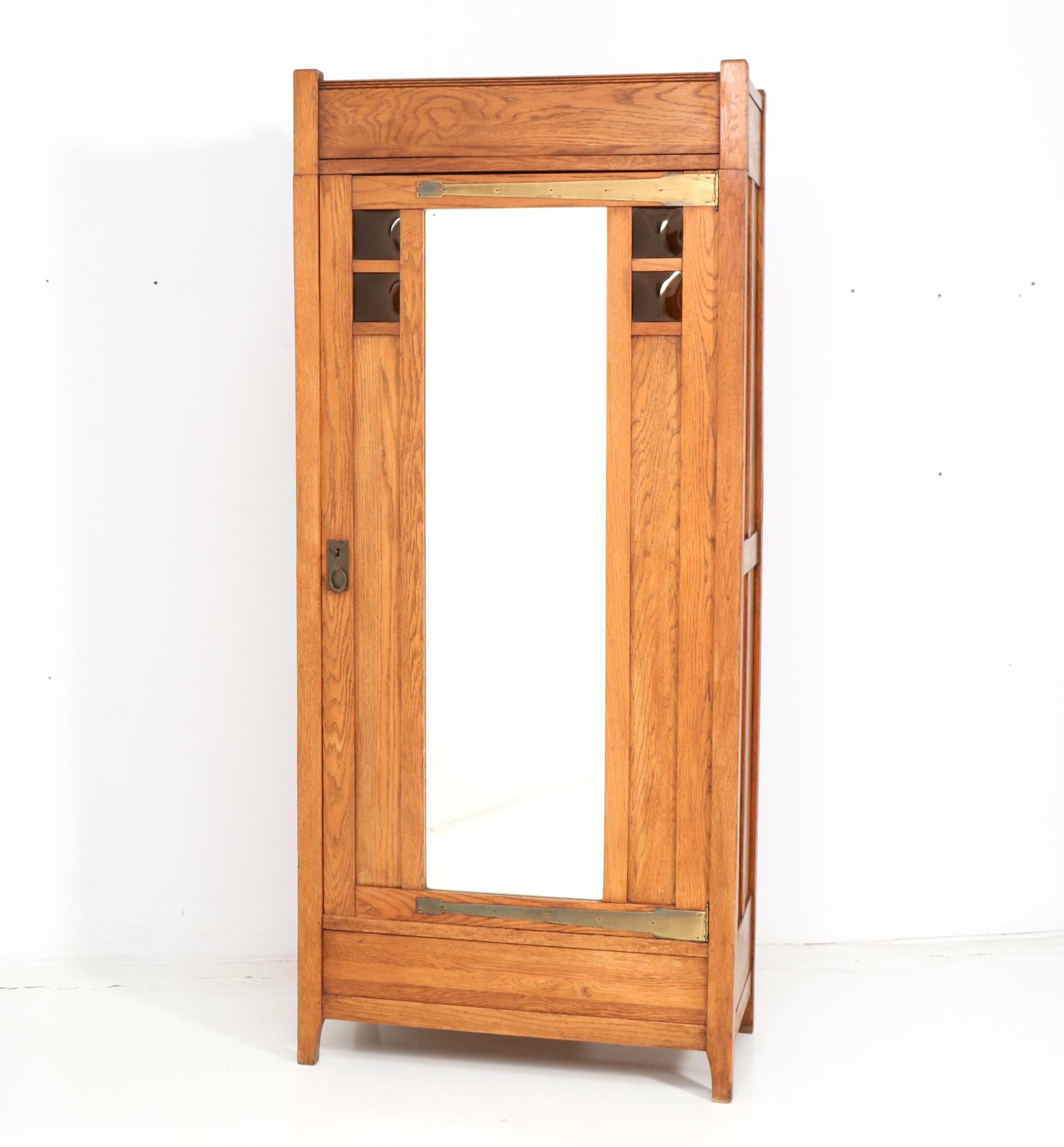 Amazing and rare Arts & Crafts Art Nouveau armoire or wardrobe.
Striking Dutch design from the 1900s.
Solid oak with original colored glass.
The door has still got the original mirrored glass.
Three stained beech shelves which are adjustable in