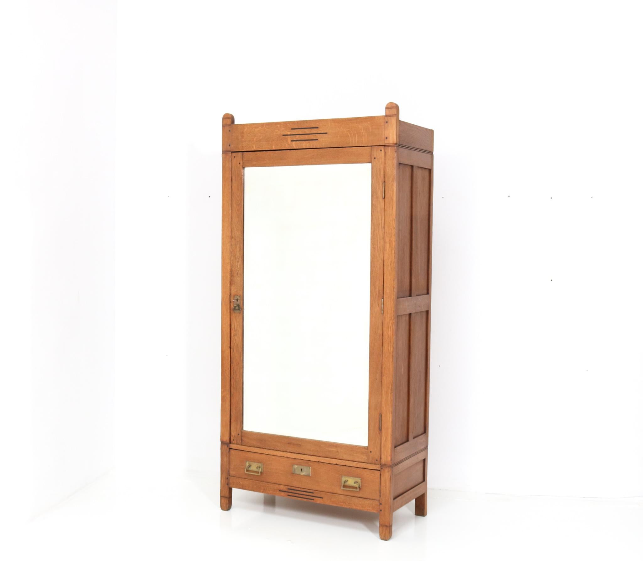 Magnificent and rare Arts & Crafts armoire or wardrobe.
Design by Phoenix Amsterdam.
Striking Dutch design from the 1900s.
Solid oak with original brass handles on door and drawer.
The door has still the original beveled mirror!
Three solid oak