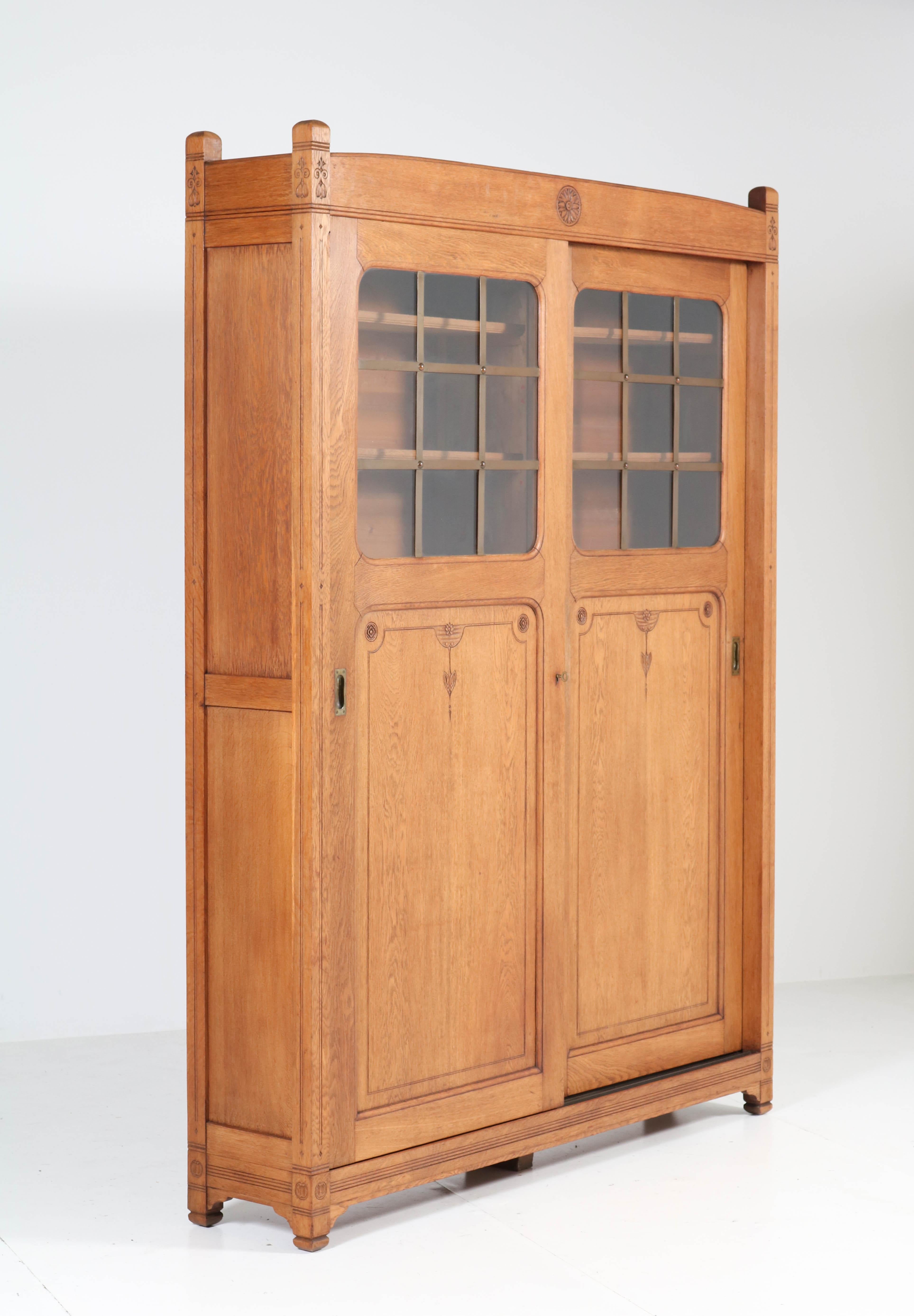 Wonderful and rare Arts & Crafts Art Nouveau bookcase.
Striking Dutch design from the 1900s.
Solid oak with two original sliding doors.
Both doors have the original glass and brass lining.
This bookcase can be dismantled for safe transport.
12