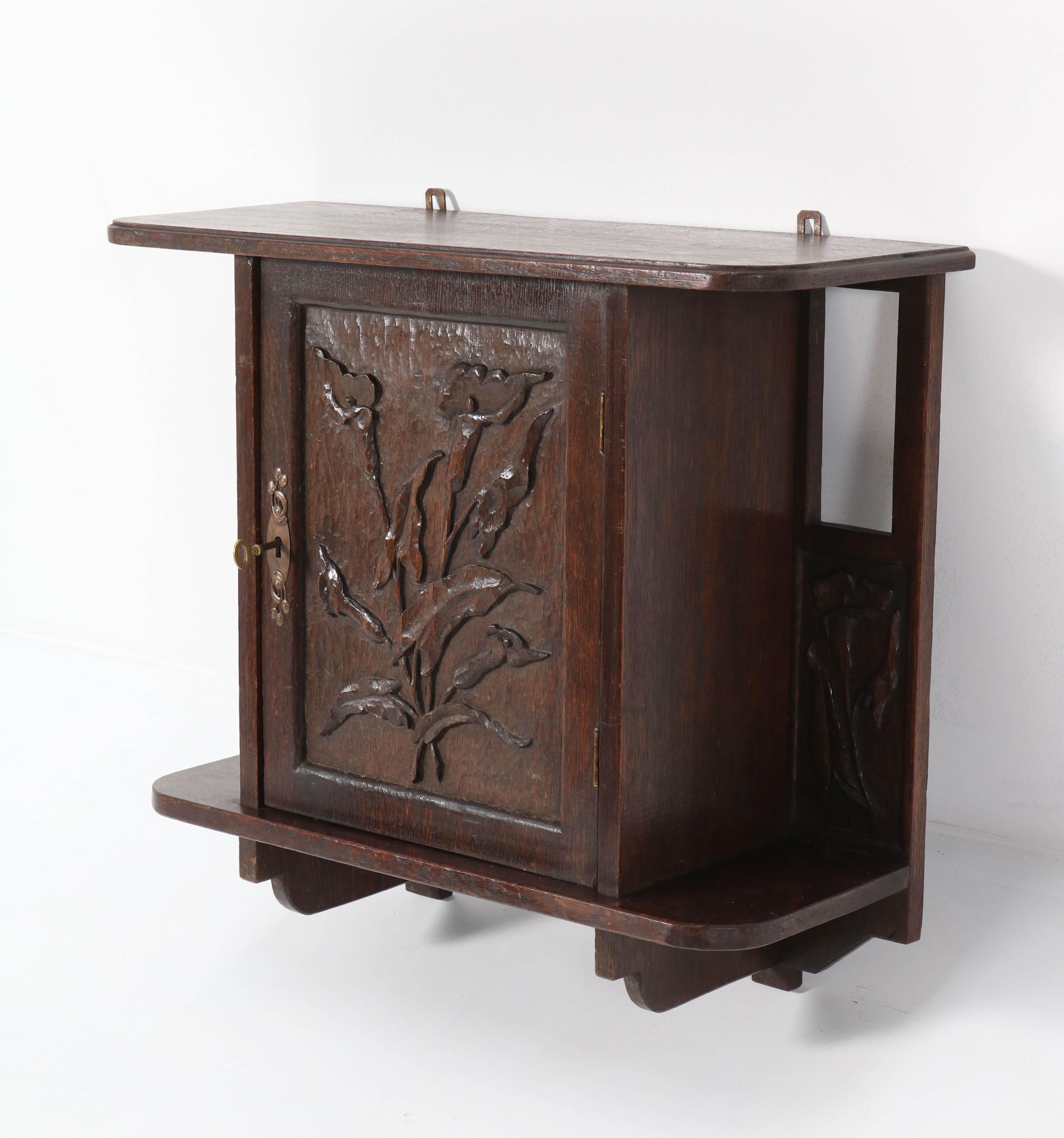 Magnificent and rare Arts & Crafts Art Nouveau wall cabinet.
Striking Dutch design from the 1900s.
Solid oak with wonderful hand carved calla lilies.
In very good condition with minor wear consistent with age and use,
preserving a beautiful