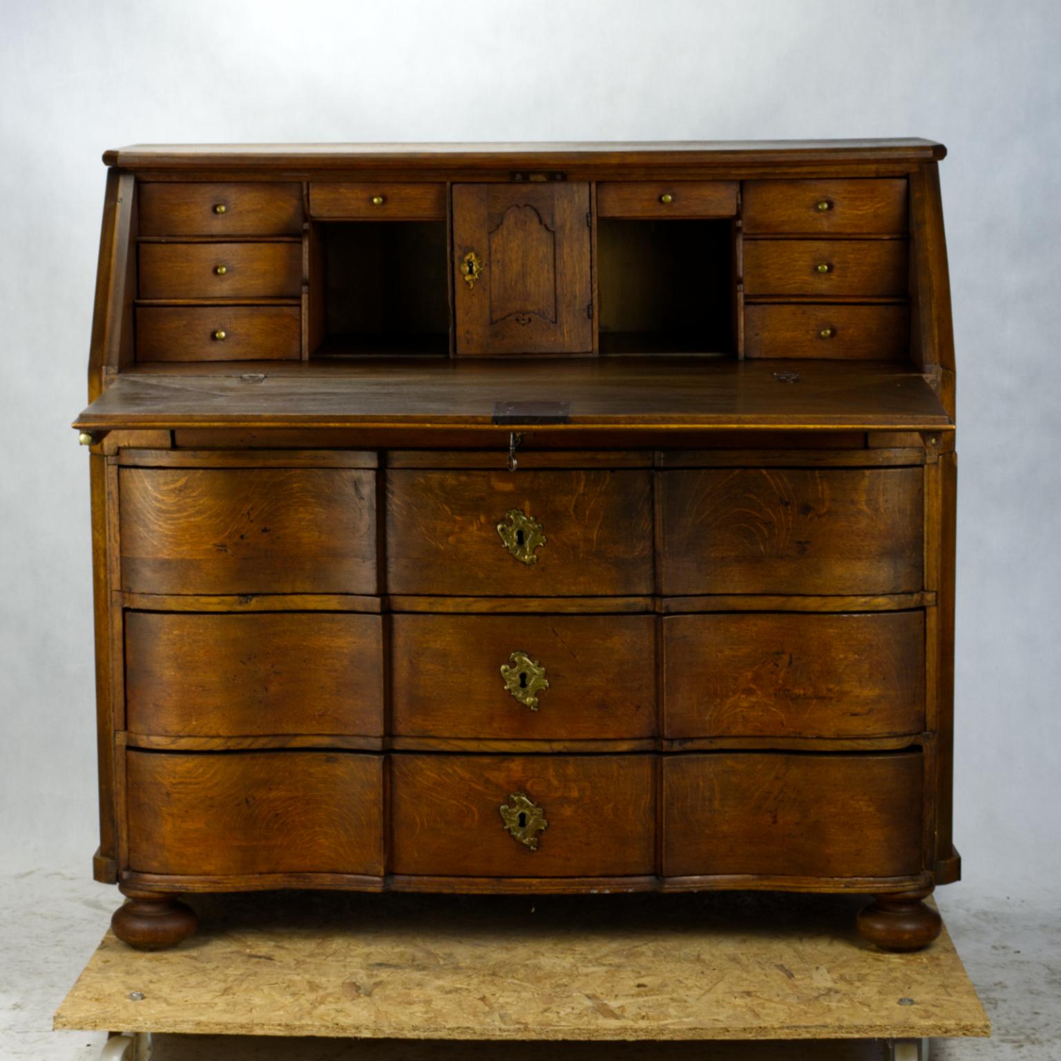 A Classic bureau in solid carved oakwood with three front profiled doors under a gorgeous secretary and writing desk from the late 18th or early 19th century. The whole chest of drawers, including drawers, is made of solid oak.
Exceptional quality
