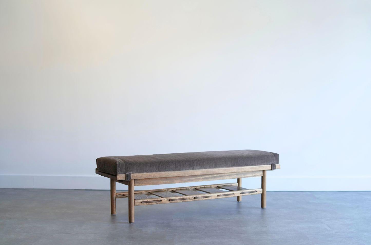 A handsome walnut bench inspired by the classic mid-century designs of Lawrence Peabody for Nemschoff Chairs, Inc., circa 1950s. This refined piece features a solid walnut frame with elegant raised edges, circular post legs, and a slatted shelf