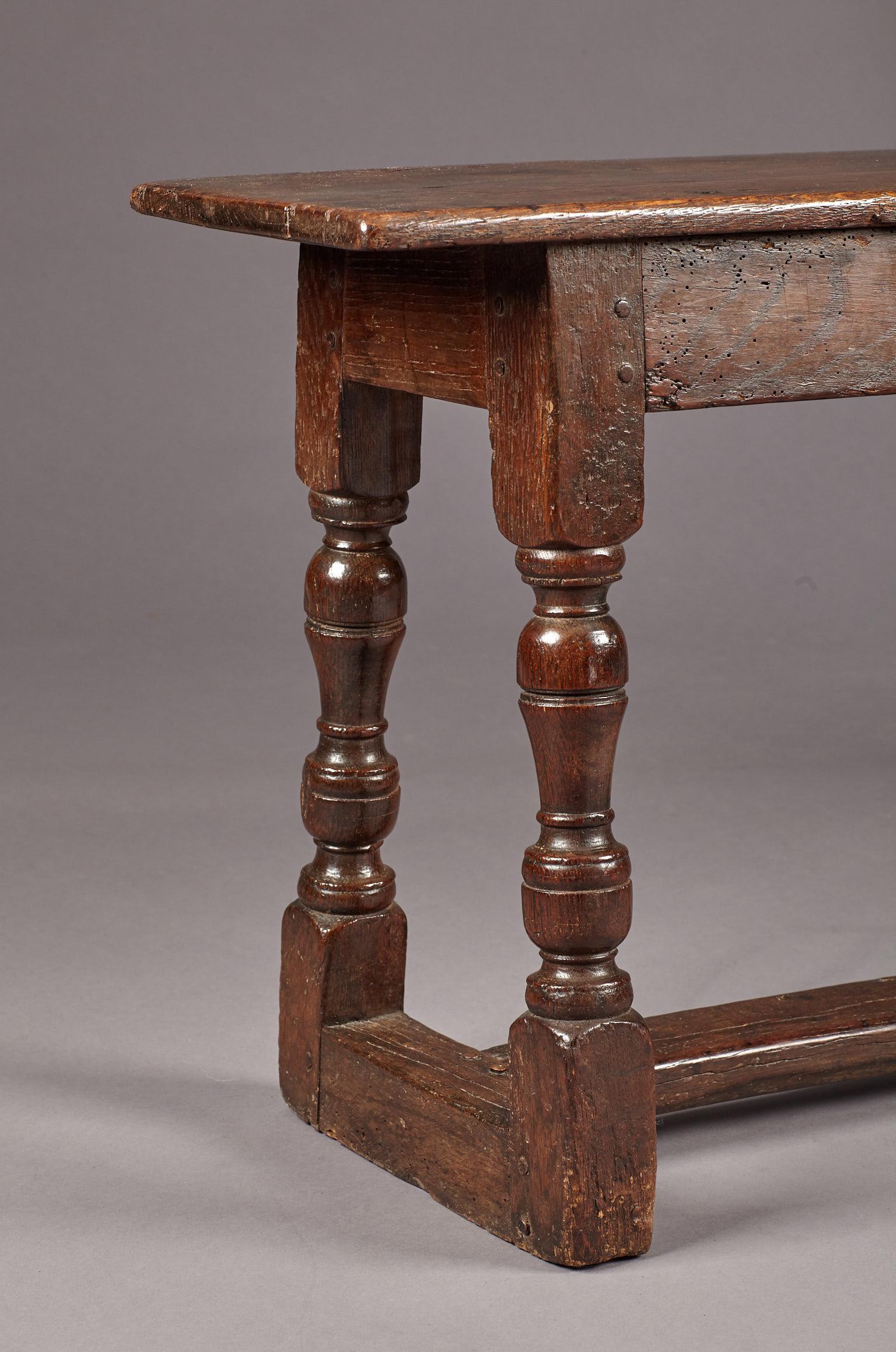 Charles I Oak 'H' stretcher bench of medium size.

The plank top bench with plain frieze rails joined by inverted baluster turned uprights and original central stretcher, with inventory brand 'I C' to frieze rail.
