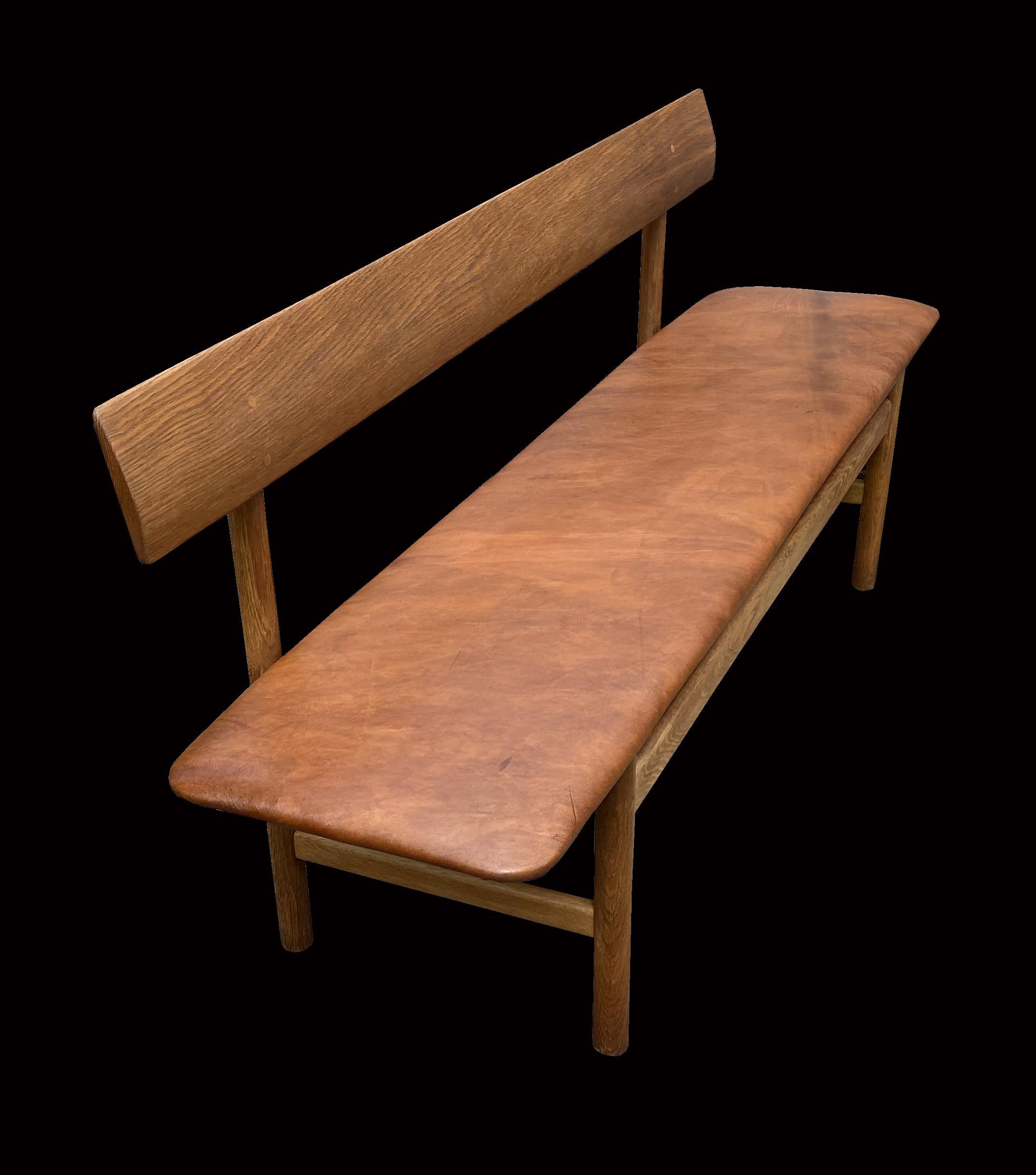 This is a very nice clean original example of this very popular bench in oak with cognac color leather seat pad, designed by Børge Mogensen and manufactured by Fredericia.