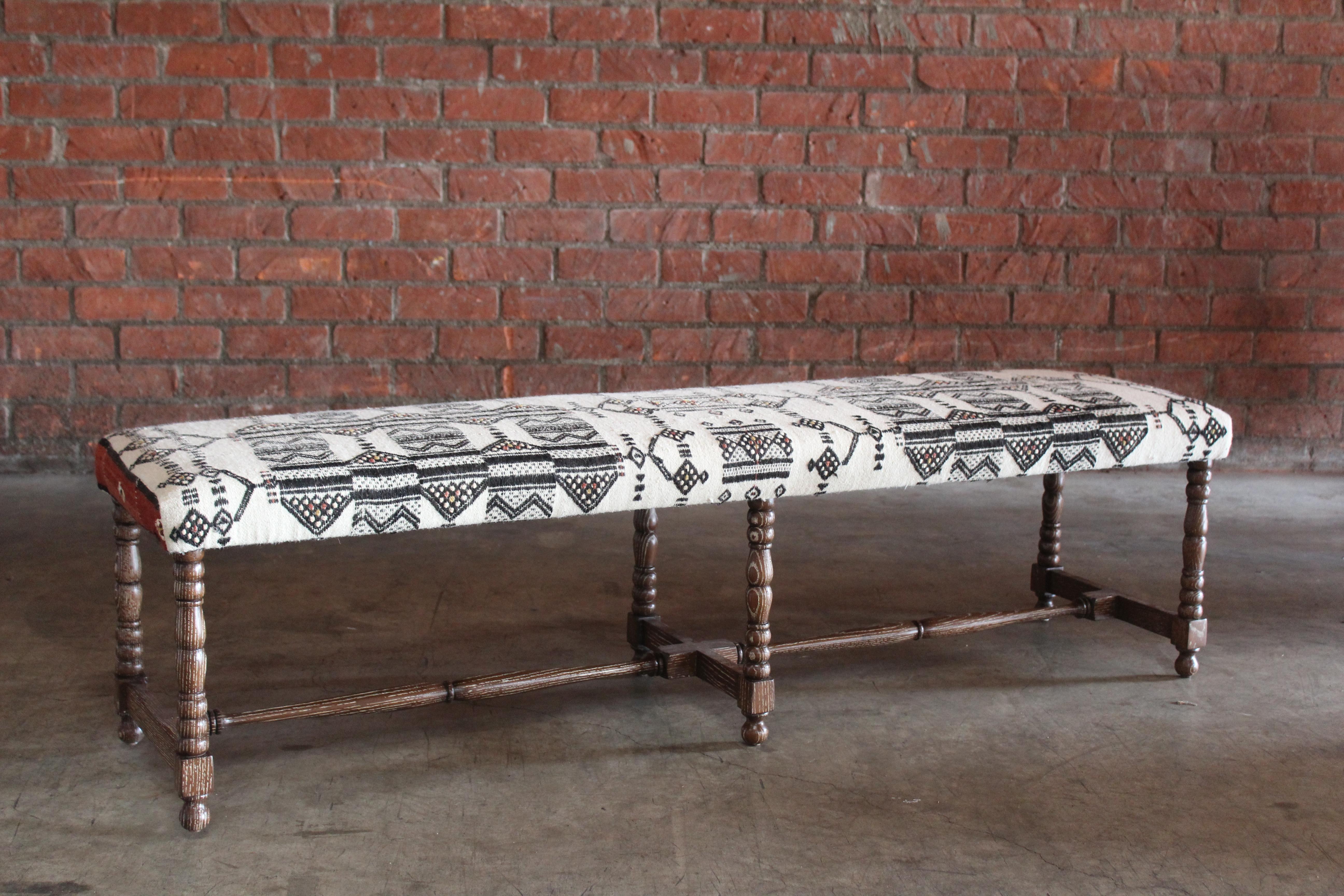 A custom bench made of solid oak- based on an antique bench. Dark cerused oak finish. Upholstered in a vintage wool Moroccan textile.