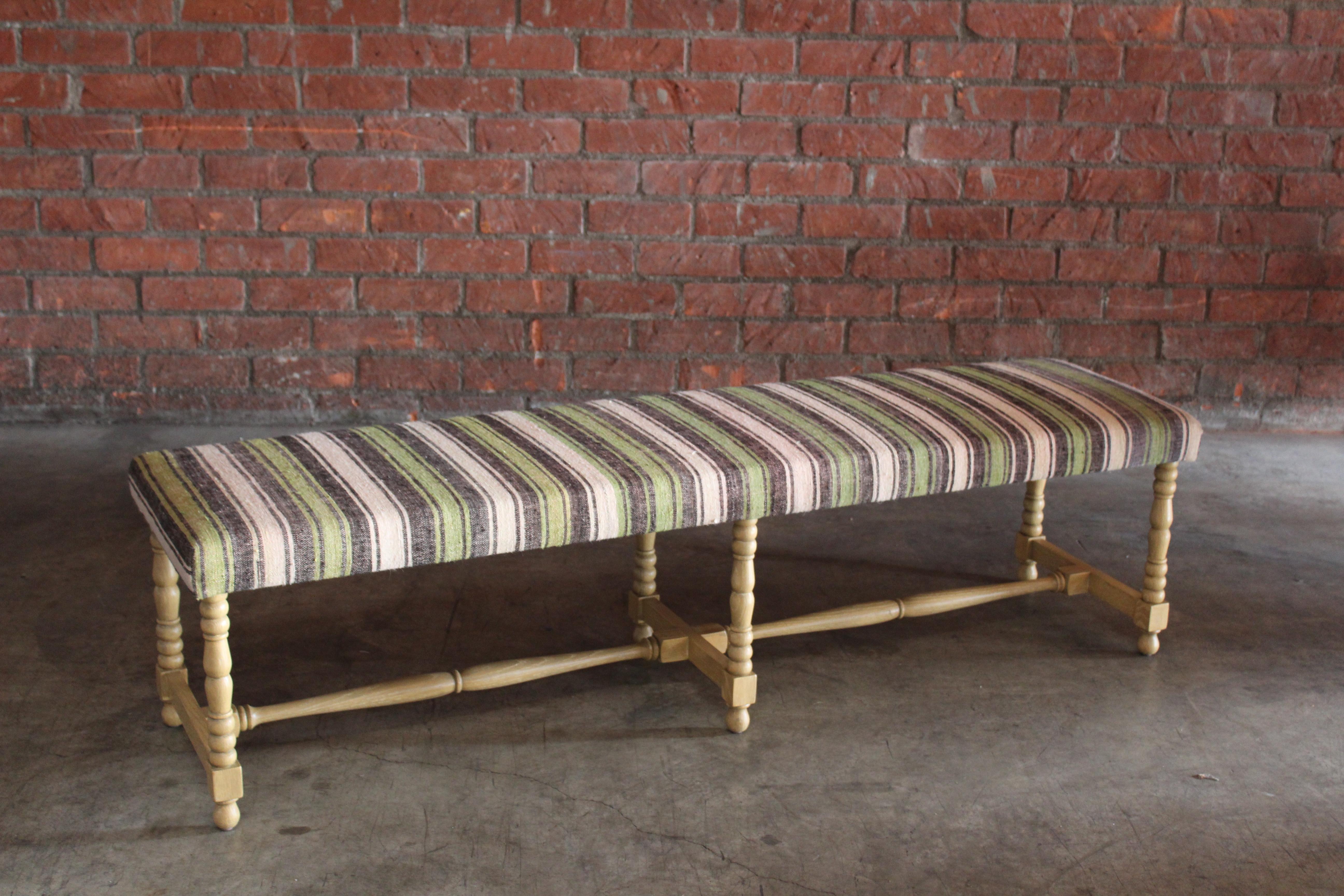 A custom handmade bench made in Los Angeles, based off an antique bench. Constructed in solid oak with a natual light finish. Upholstered in a vintage Turkish striped wool rug. In overall excellent condition.