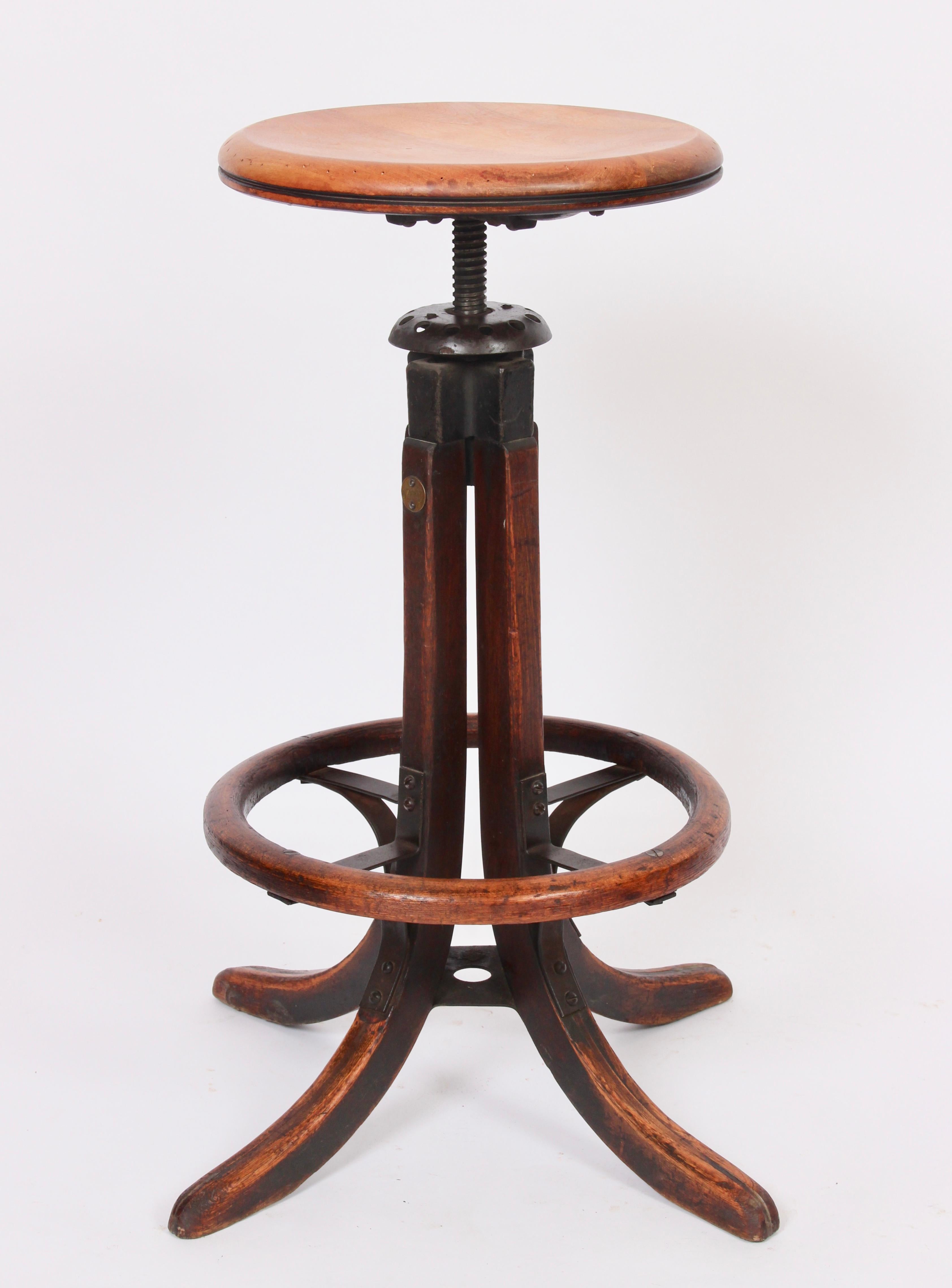 Industrial early 20th century adjustable height oak and iron architects, artists swivel stool. Featuring a sturdy reinforced splayed four-legged oak base, original circular oak heel ring also reinforced with metal bracing, refinished and varnished