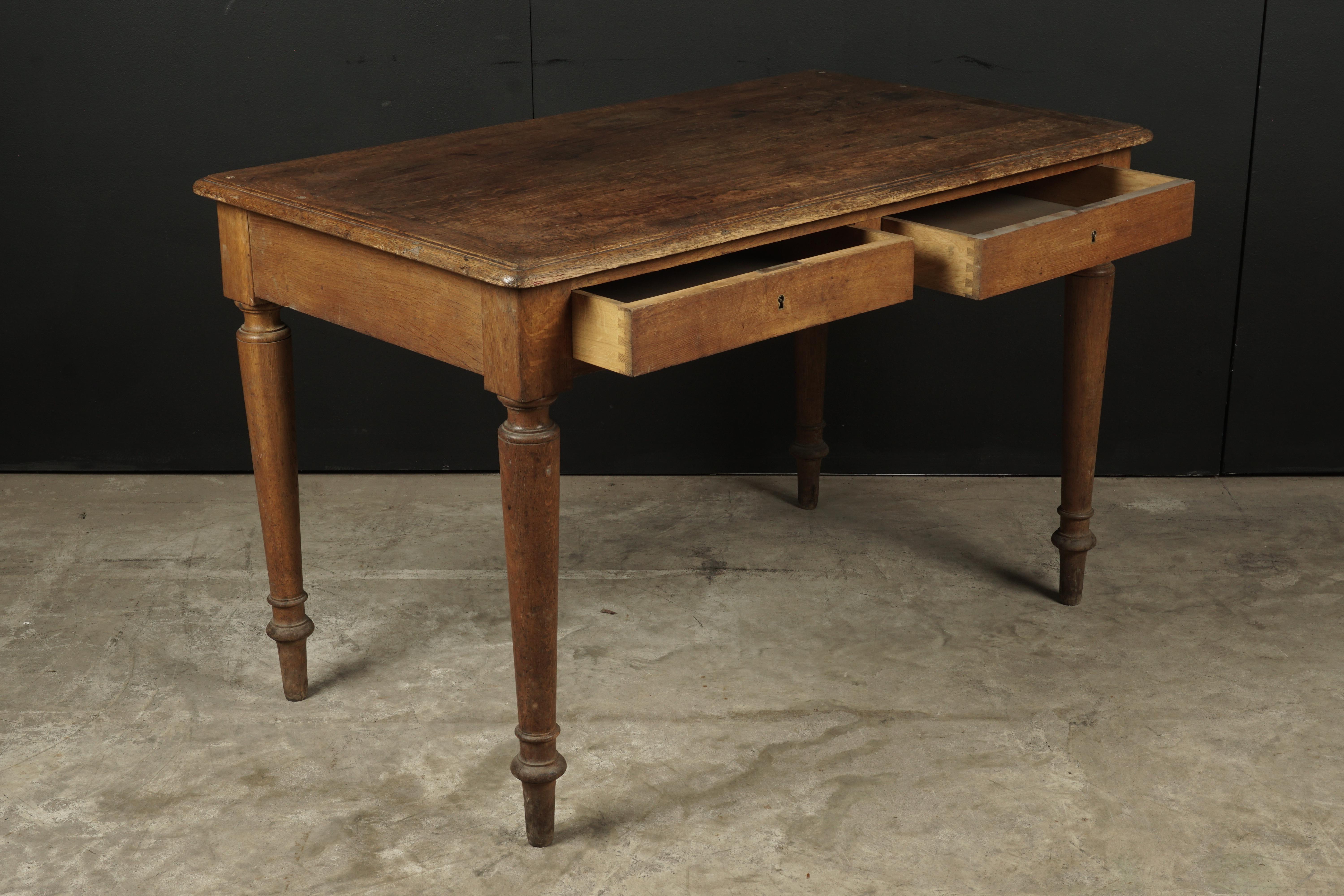 Oak bistro table from France, circa 1940. Solid oak construction with two drawers and baluster legs.