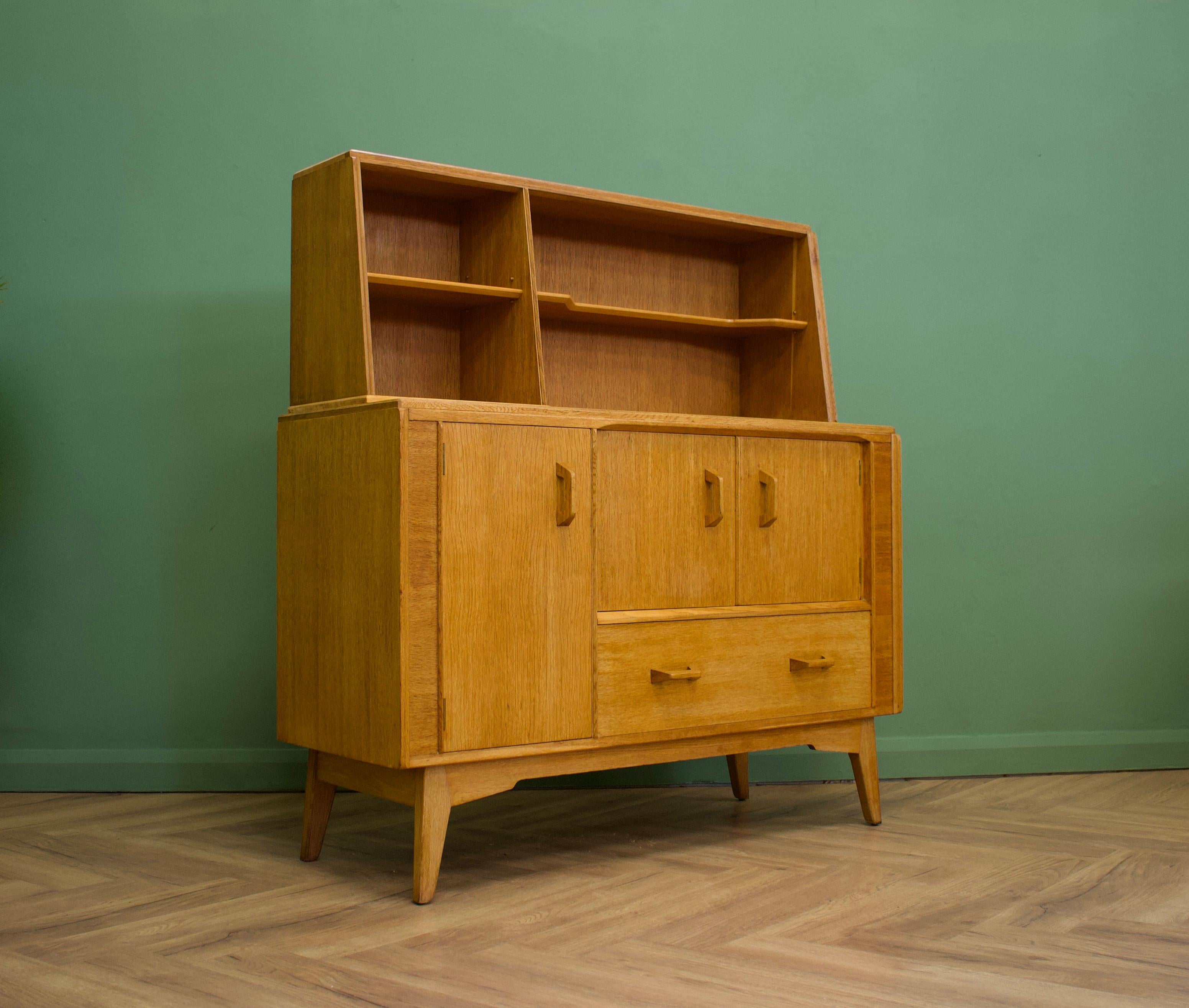 A midcentury oak sideboard from G Plan - from the Brandon range.

Featuring a drawer, two cupboards and shelves to the top.

The top section is removable, but there lighter mark where it sits.