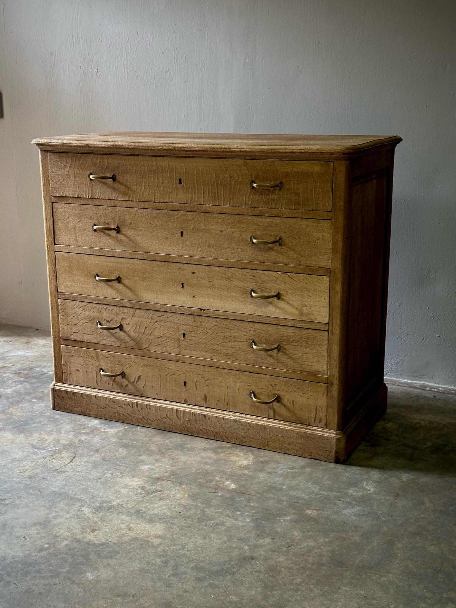 Slightly rustic French chest of drawers in sun bleached oak. Brass finish hardware and keyhole details tastefully and minimally embellish this set of five functional drawers. 

France, circa 1920

Dimensions: 49W x 22D x 42H