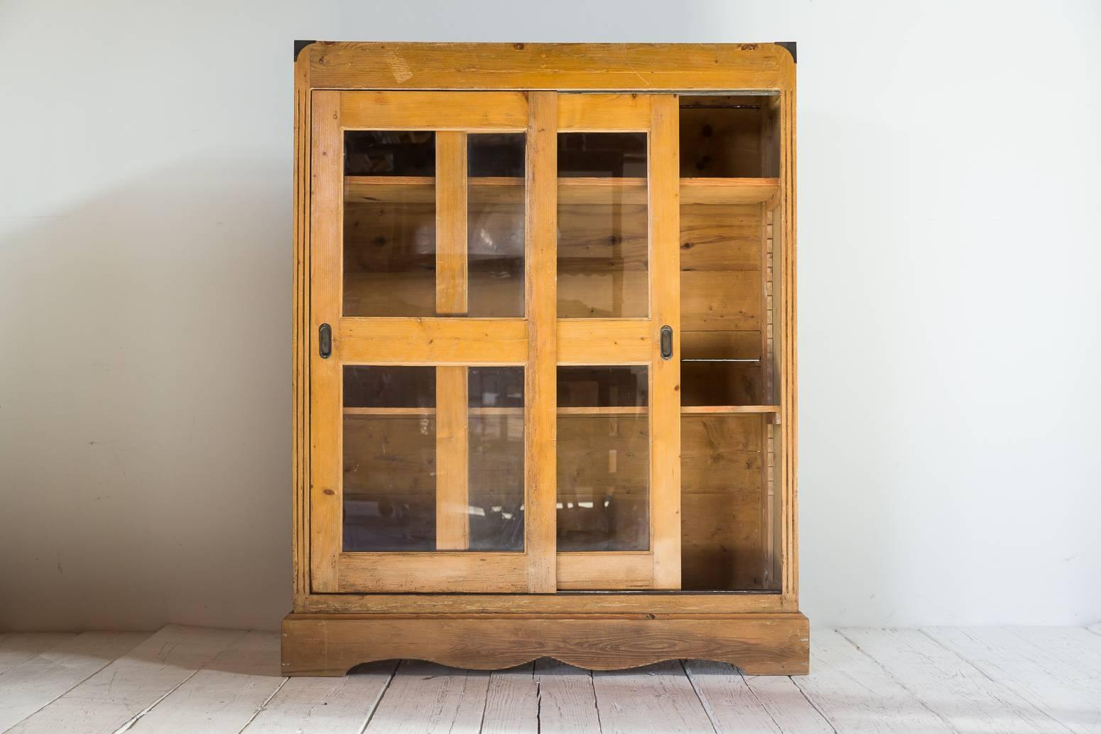 Oak cabinet with glass sliding doors. Scrolled base with Campaign style hardware. Two interior adjustable shelves.
