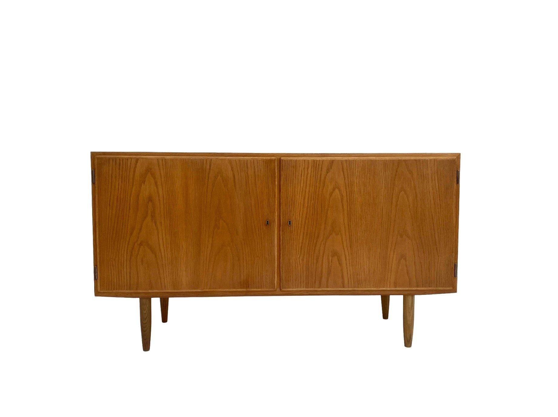 A beautiful Danish oak sideboard designed by Carlo Jensen for Poul Hundevad, this would make a stylish addition to any living or work area.

The cabinet has a cupboard to both ends one with two adjustable shelves and the other with three removable