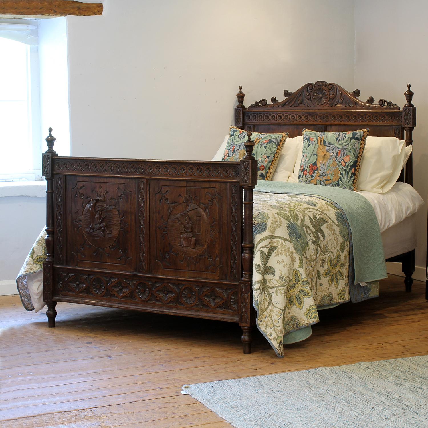 An elaborately carved oak French Breton bed from the early Twentieth century, with decoratively carved panels on the foot board depicting a man and woman in rural setting, turned posts and decorative pediment on the head end.

This bed accepts a US