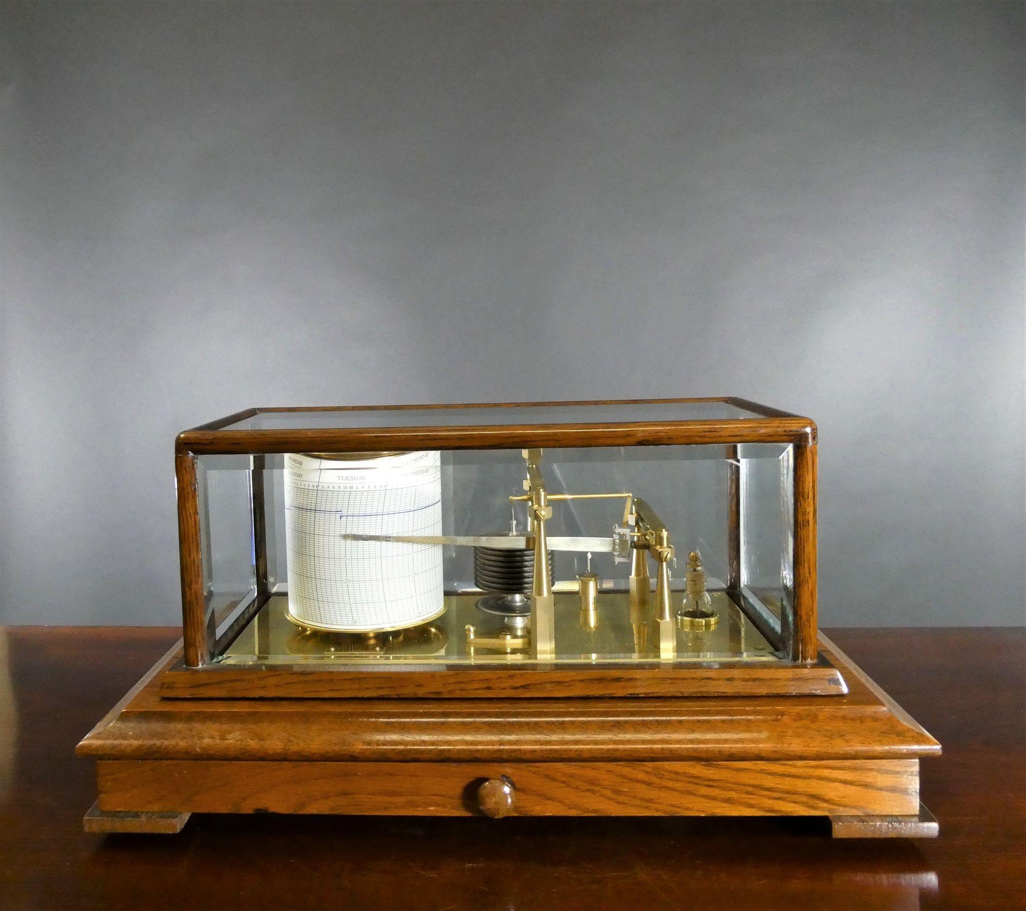 NEGRETTI  &  ZAMBRA
 
Barographe édouardien en chêne avec panneaux en verre biseauté et tiroir central pour les cartes.
Dix chambres à vide reliant le bras enregistreur au mouvement de huit jours au tambour circulaire rotatif avec échappement à