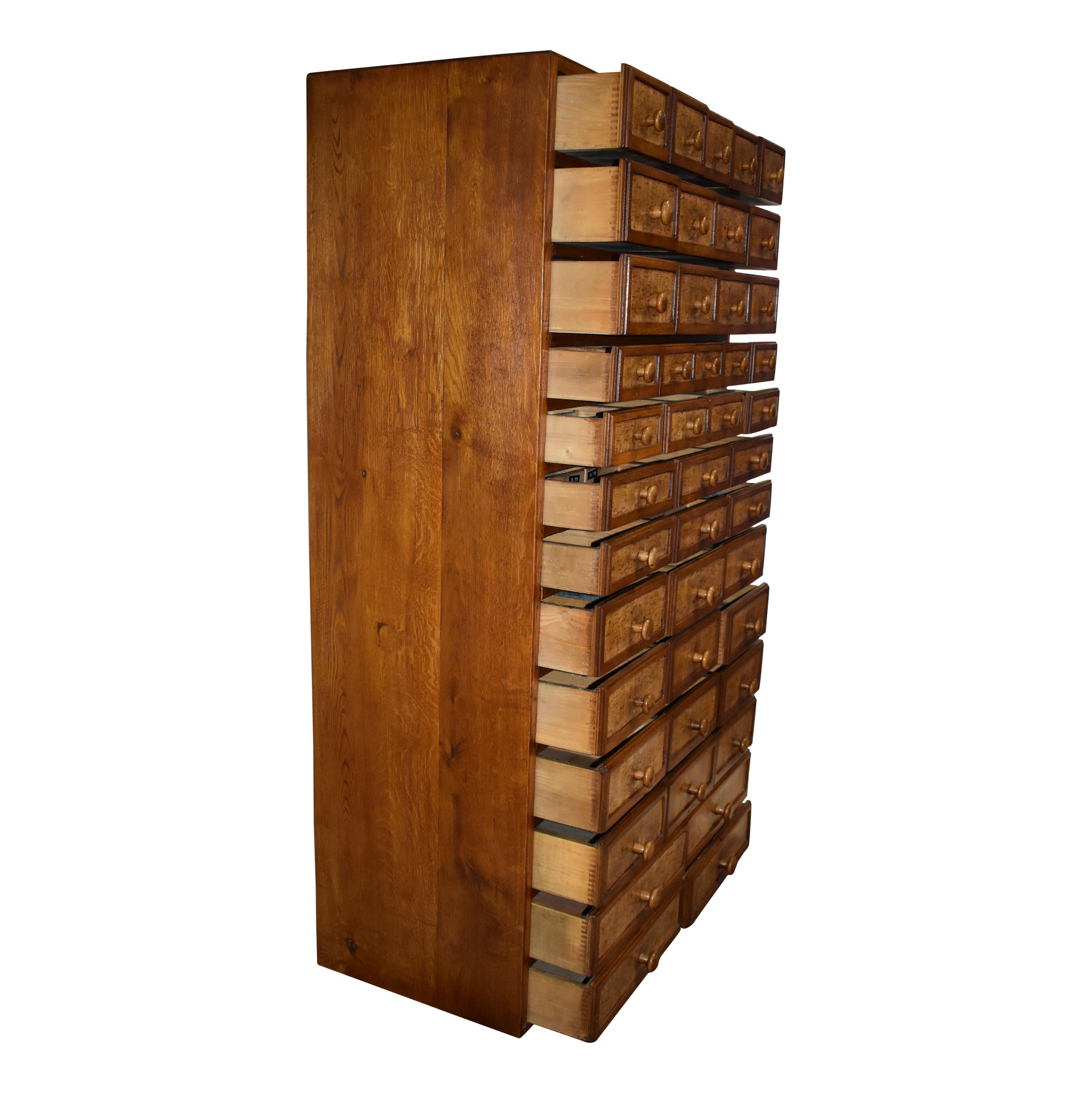 Featuring 44 dovetailed drawers of various sizes with wooden knob pulls, this oak cabinet was once used for cataloging auto information and small parts.
 
