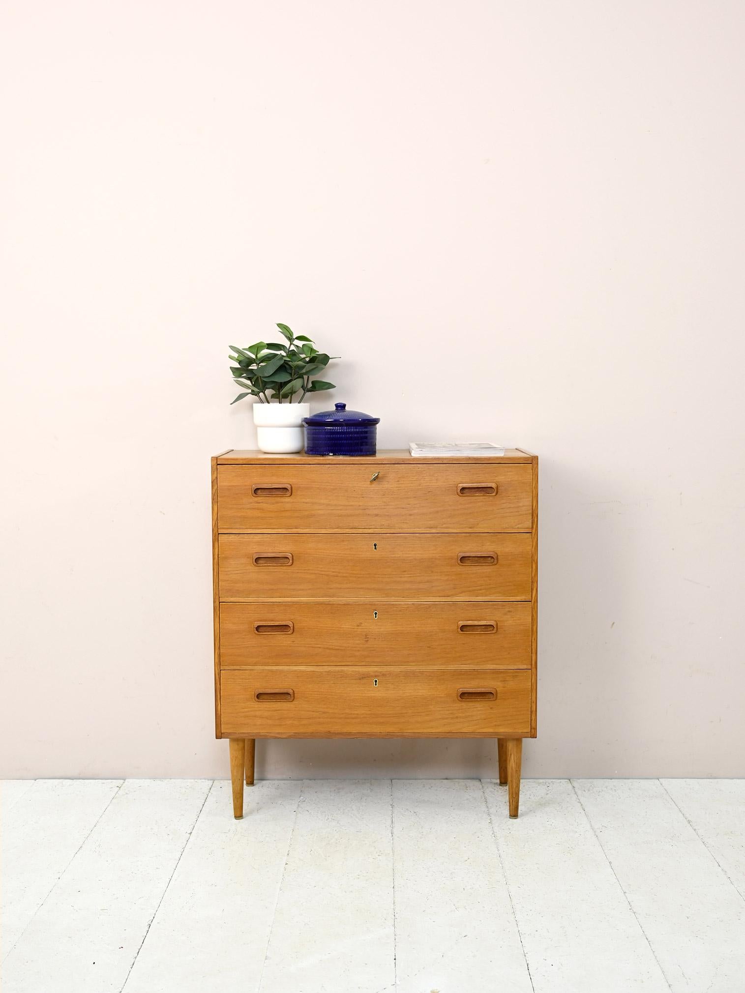 Swedish modern antique cabinet with drawers.

Scandinavian chest of drawers with 4 drawers, original 1960s teak.
The frame is simple and square in contrast to the curved handle of the carved wooden handles and tapered legs.
The lockable drawers