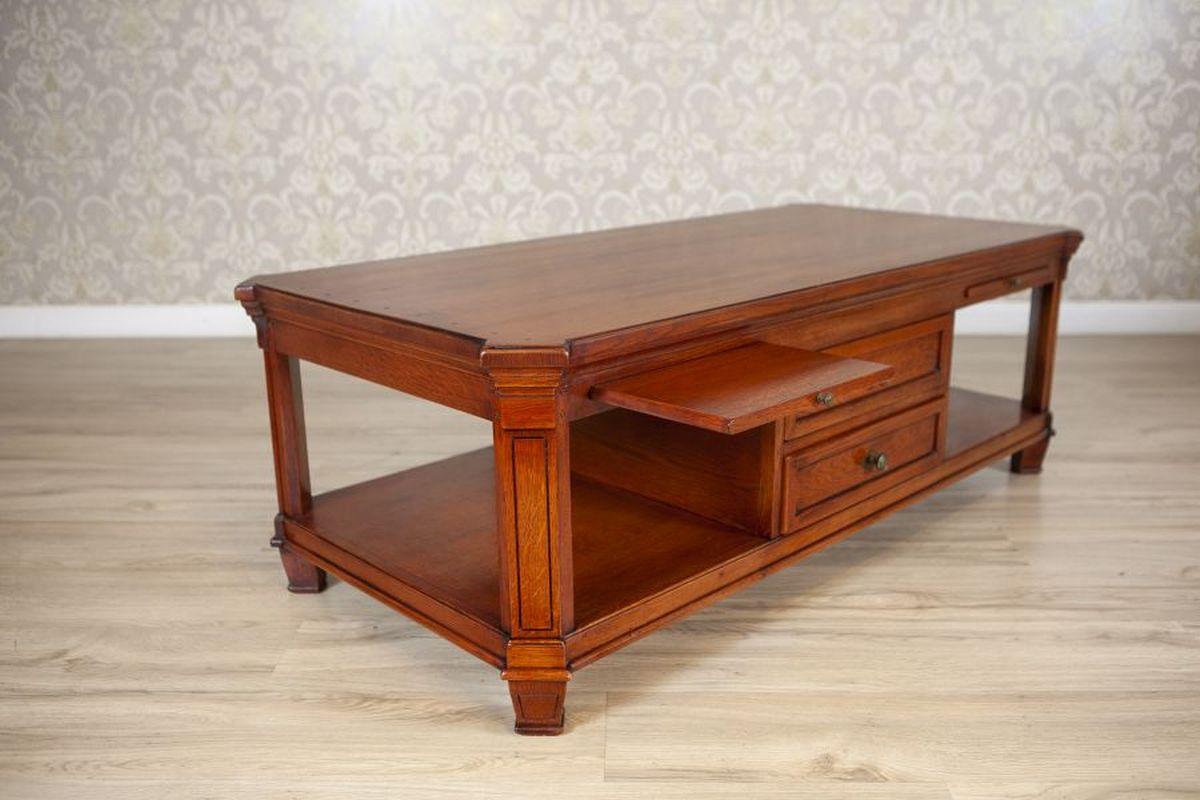 Oak Coffee Table With Drawers From the Mid. 20th Century

A rectangular oak wood coffee table, supported by straight legs. The apron features sliding panels, with two drawers in the center and a sturdy lower shelf for added storage.

The table has