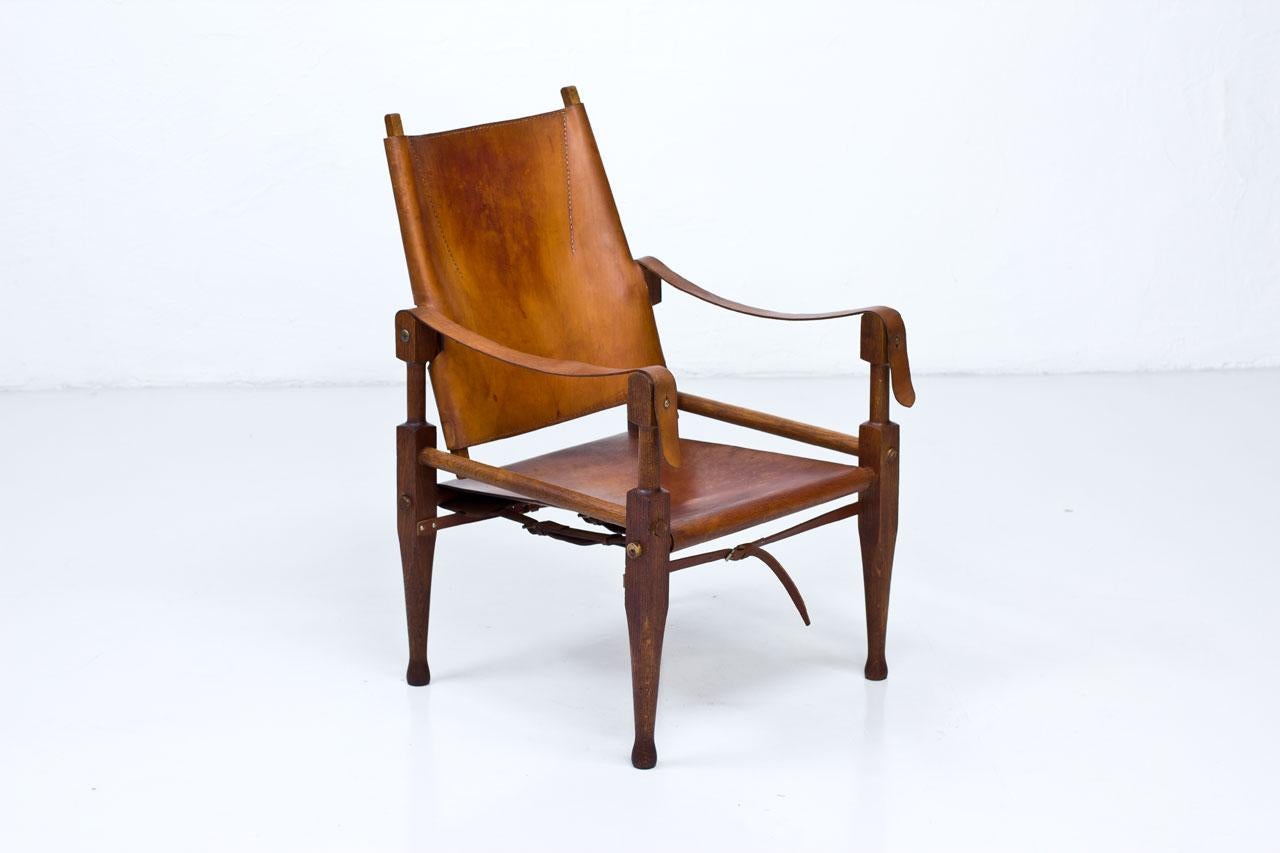Safari chair designed by Wilhelm Kienzle produced by Wohnbedarf in Switzerland during the 1950s. Solid oak frame with original thick cognac leather upholstery.