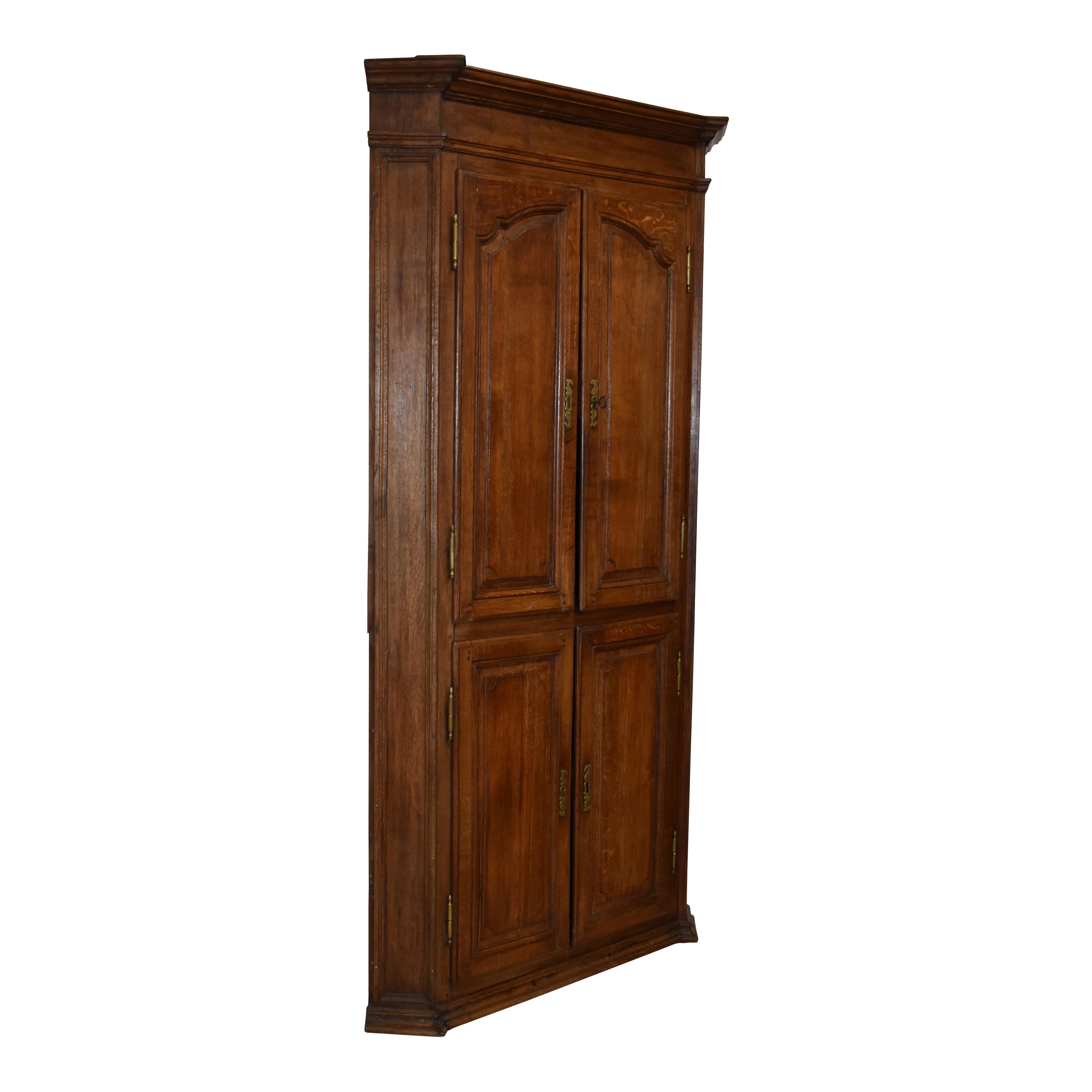Simple yet stately, this corner cabinet was crafted from solid oak and finished with a medium stain at the beginning of the 20th century. The cabinet's corner design maximizes storage without sacrificing floor space. Although the cabinet appears to