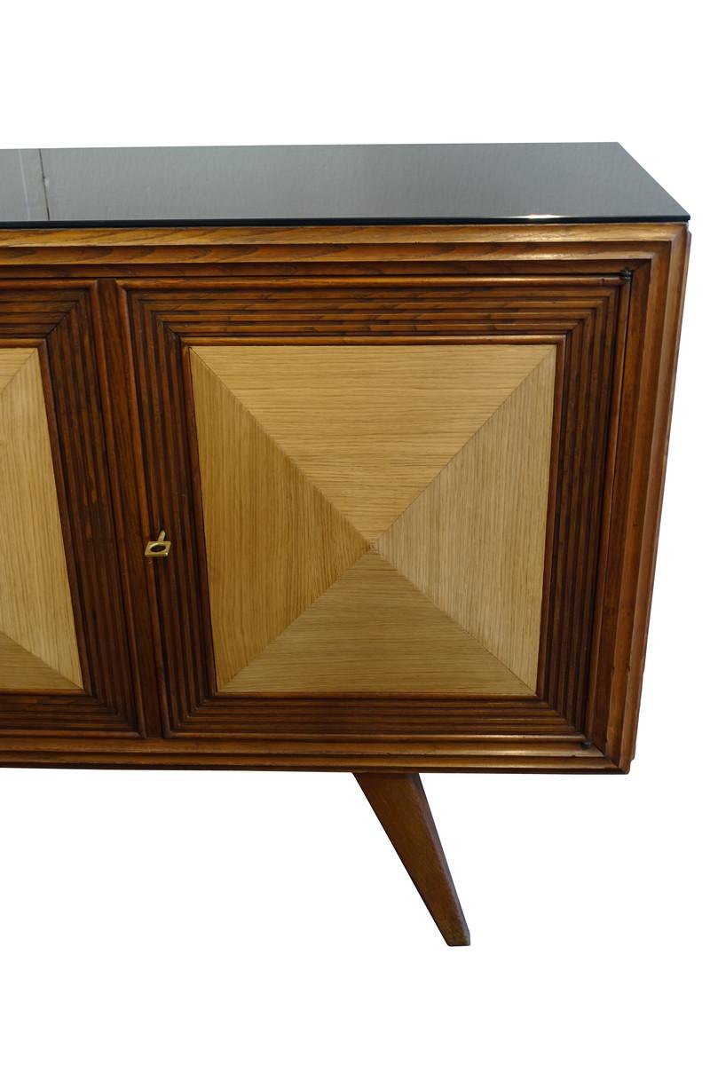 Midcentury Italian credenza with raised and mitered pyramid shaped front panels of bleached oak
Cabinet made of Durmast oak
Four doors
Black glass top
Two interior shelves.
 